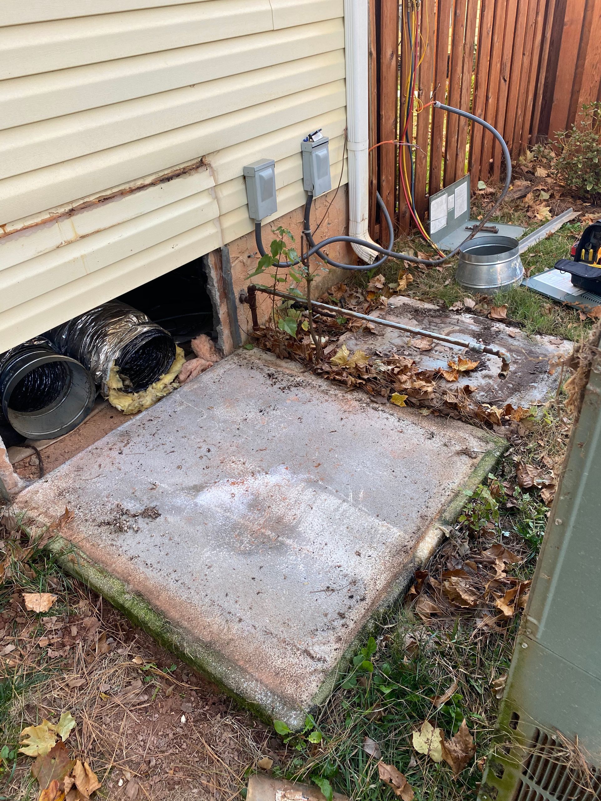 A concrete slab is sitting under a house next to a fence.