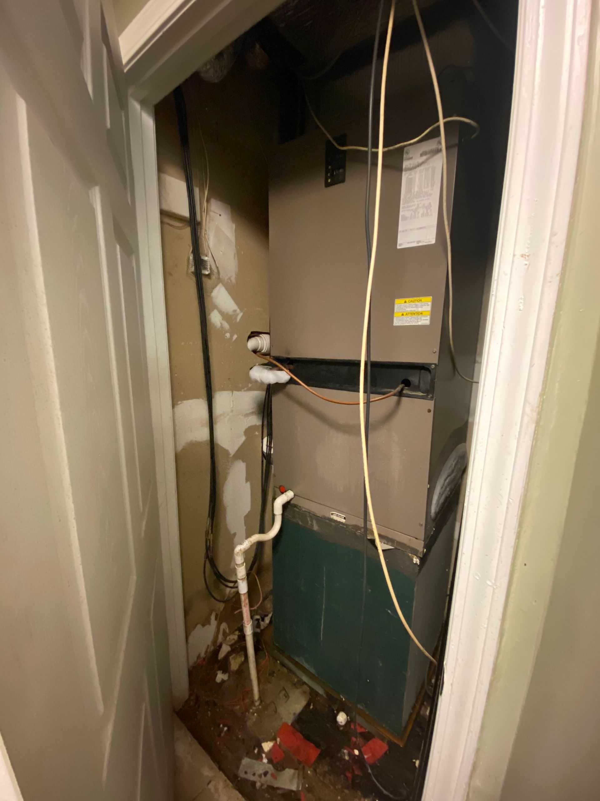 An old air conditioner is sitting in a closet next to a door.
