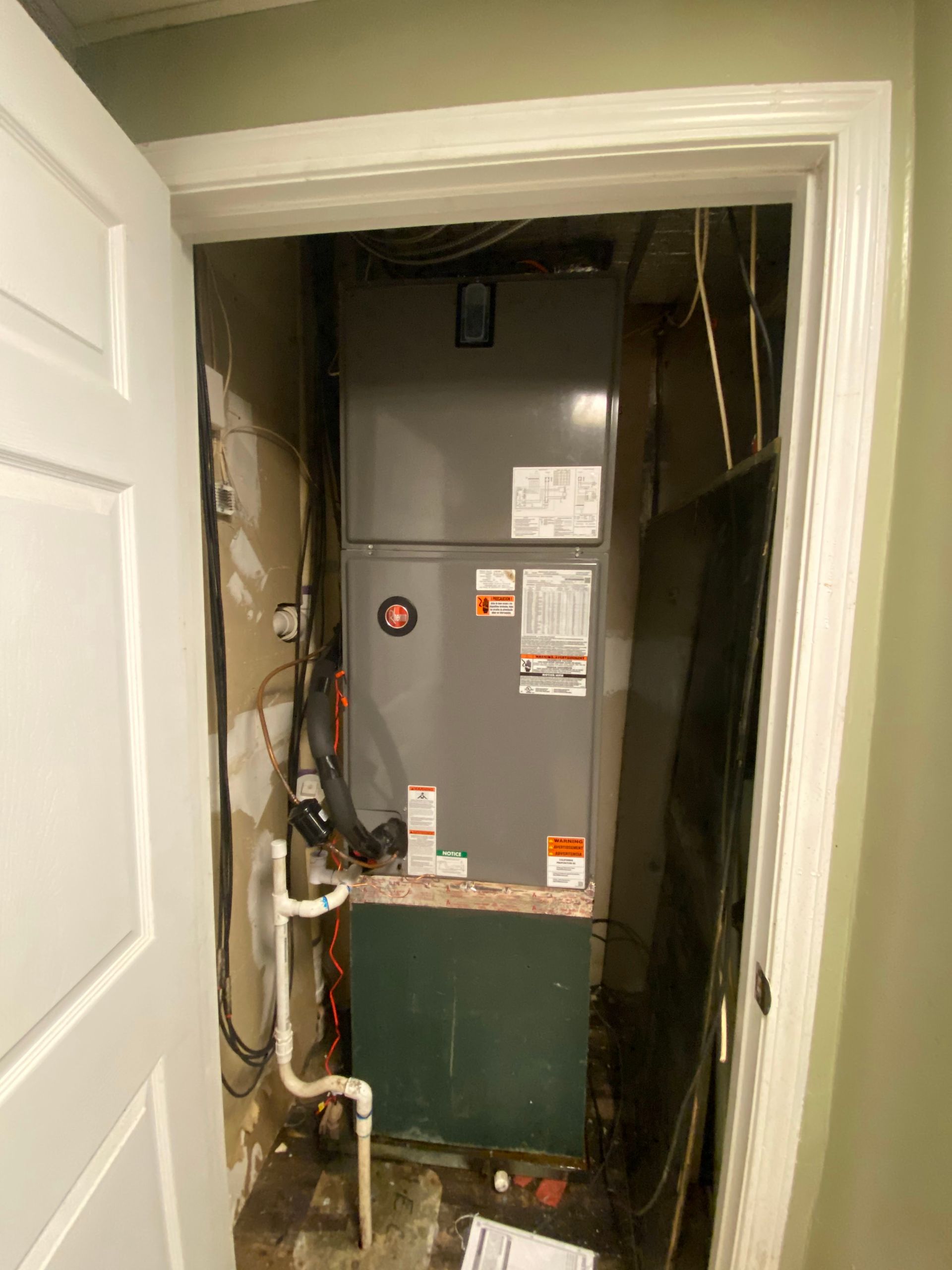 An air conditioner is sitting inside of a doorway in a room.