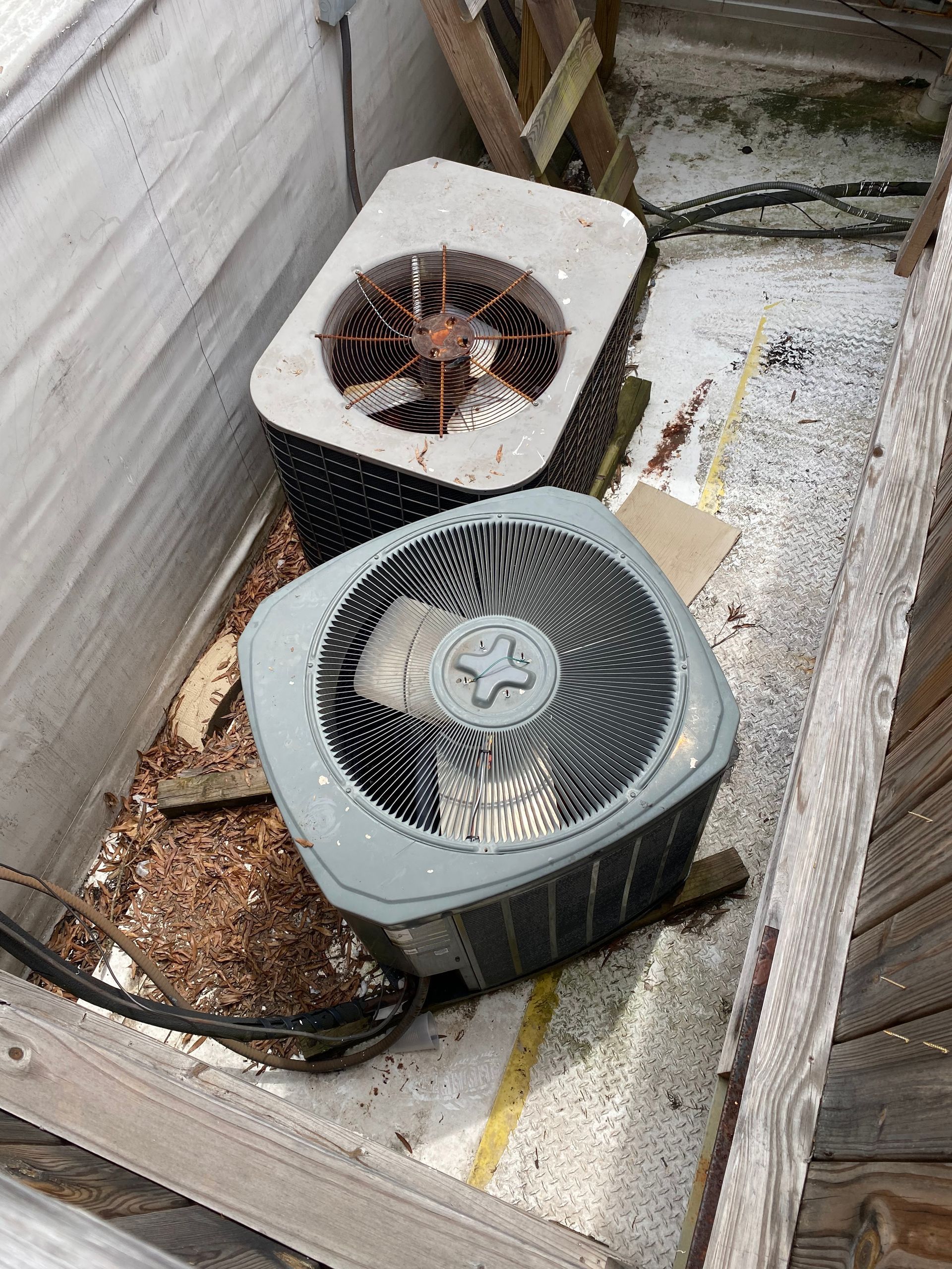 Two air conditioners are sitting on top of a wooden box.
