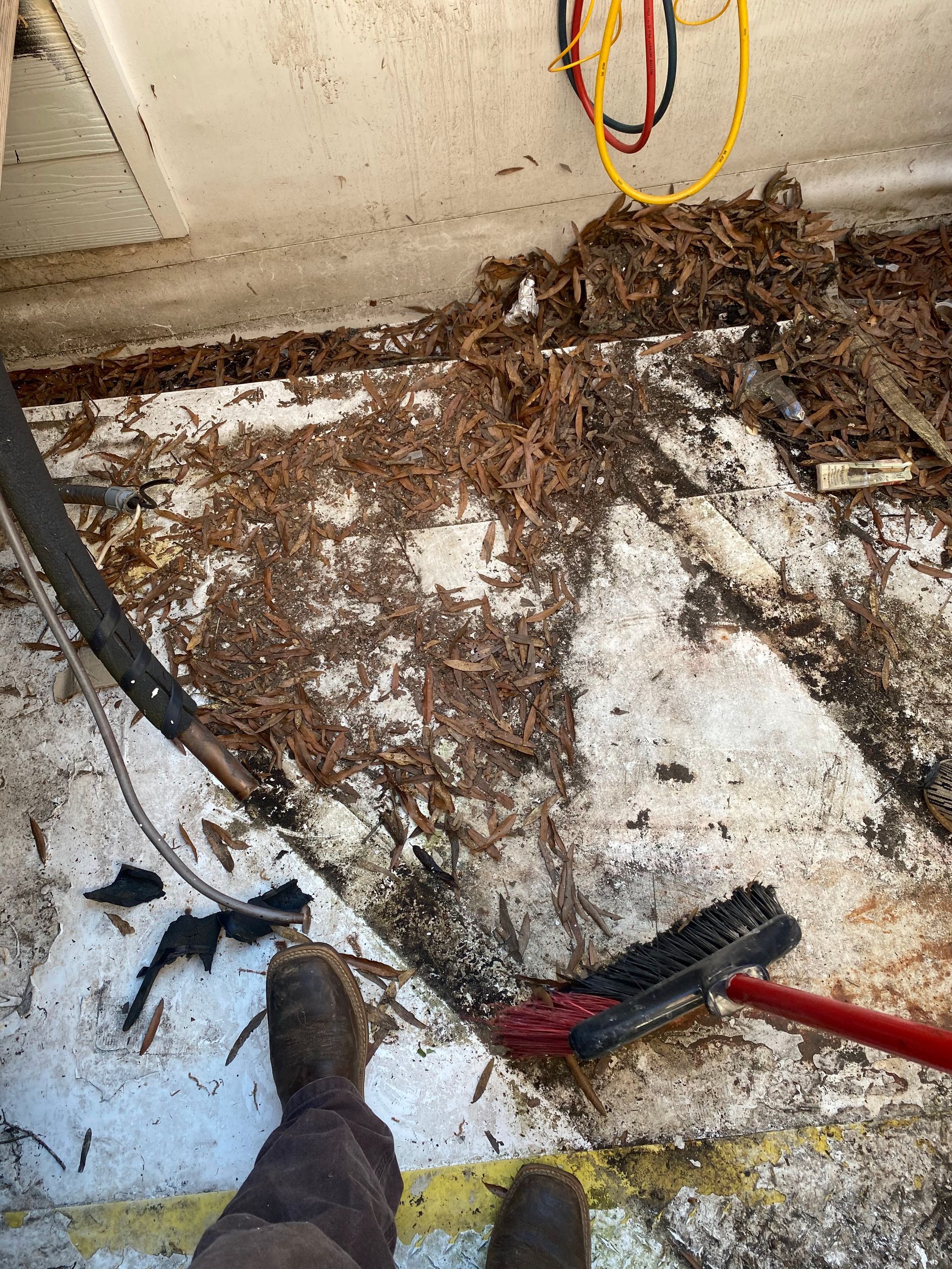 A person is standing on a dirty floor next to a broom.