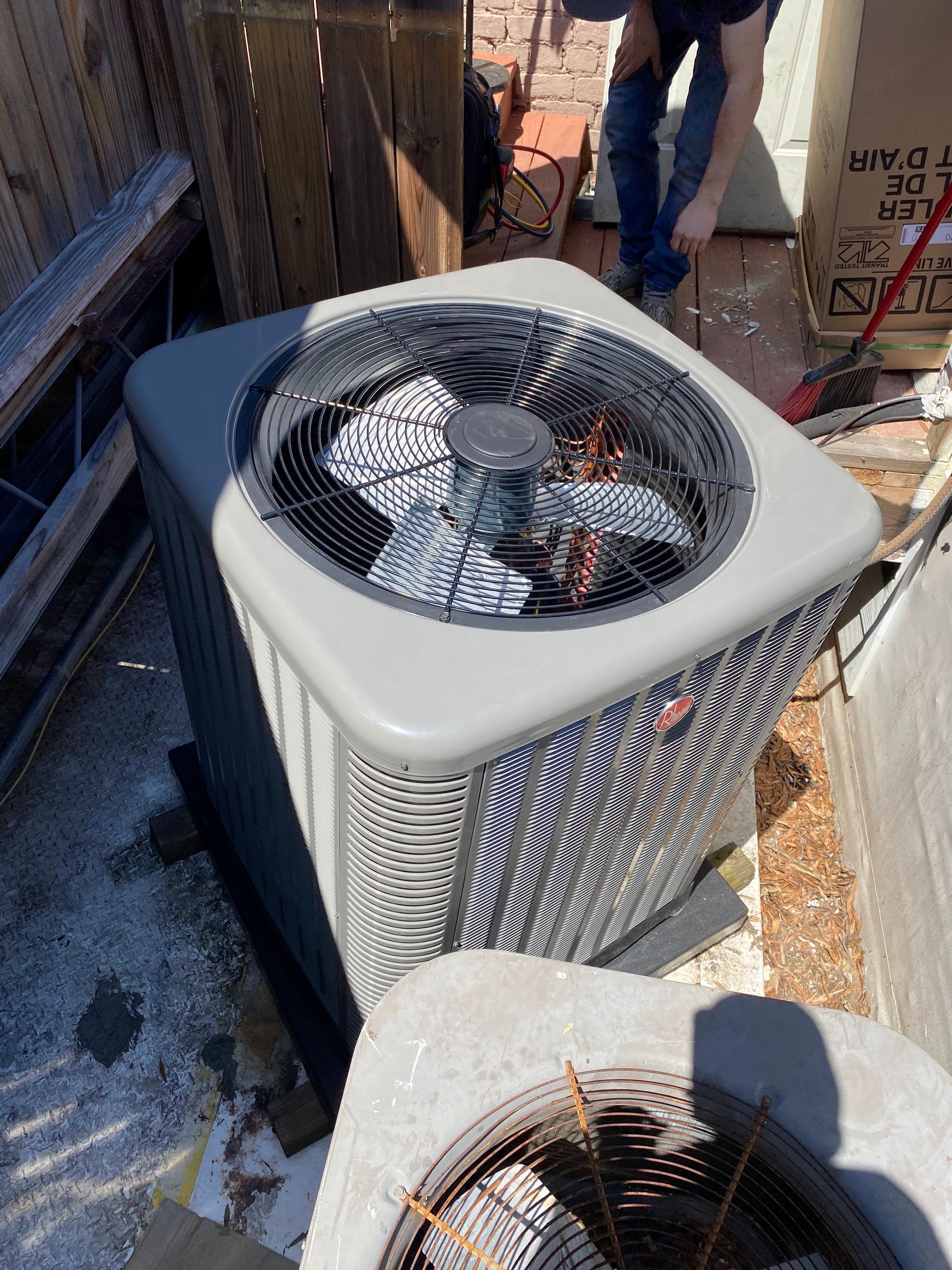 A man is working on an air conditioner on a roof.