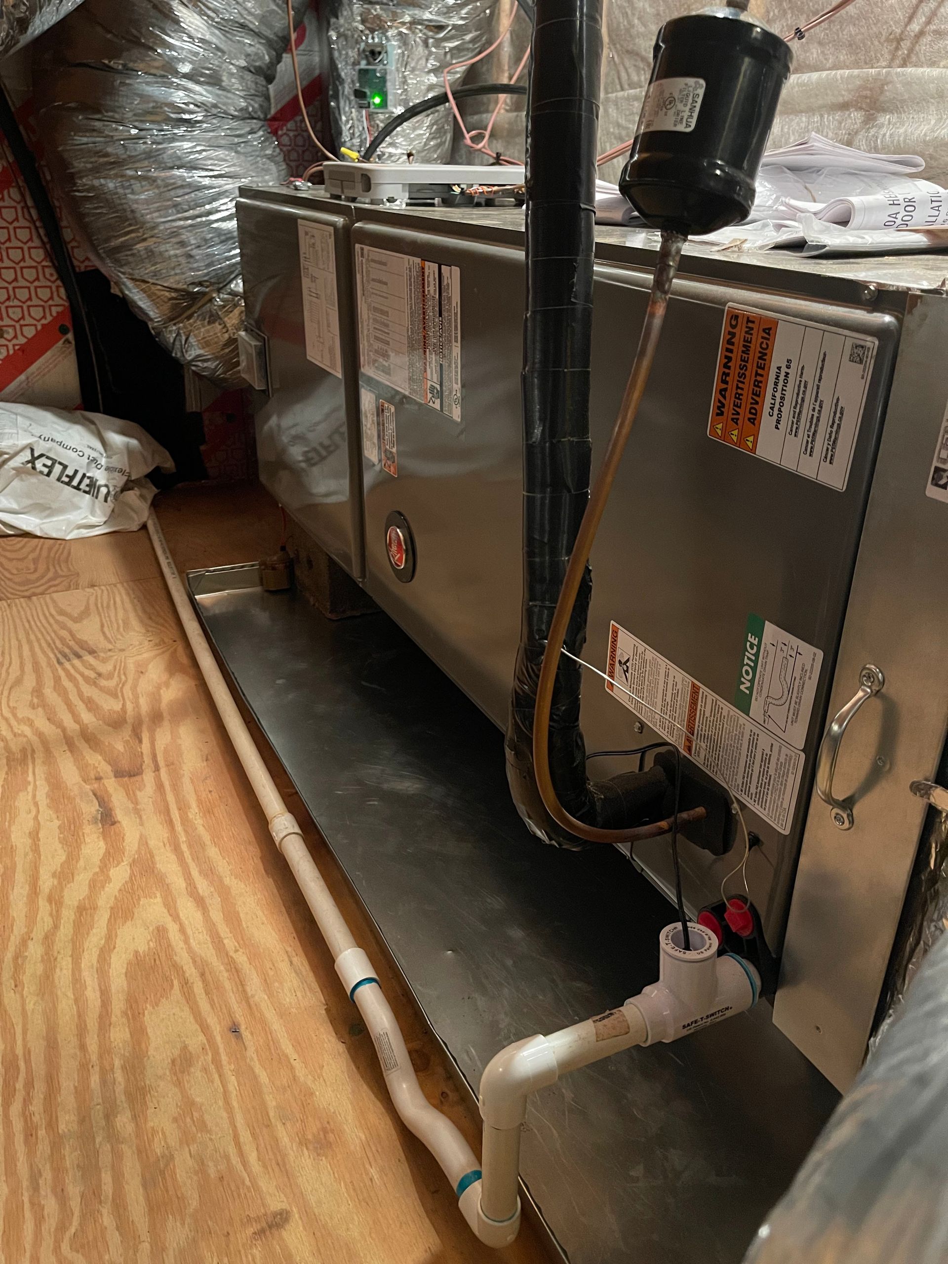 A heating and cooling system is sitting on a wooden floor in a room.