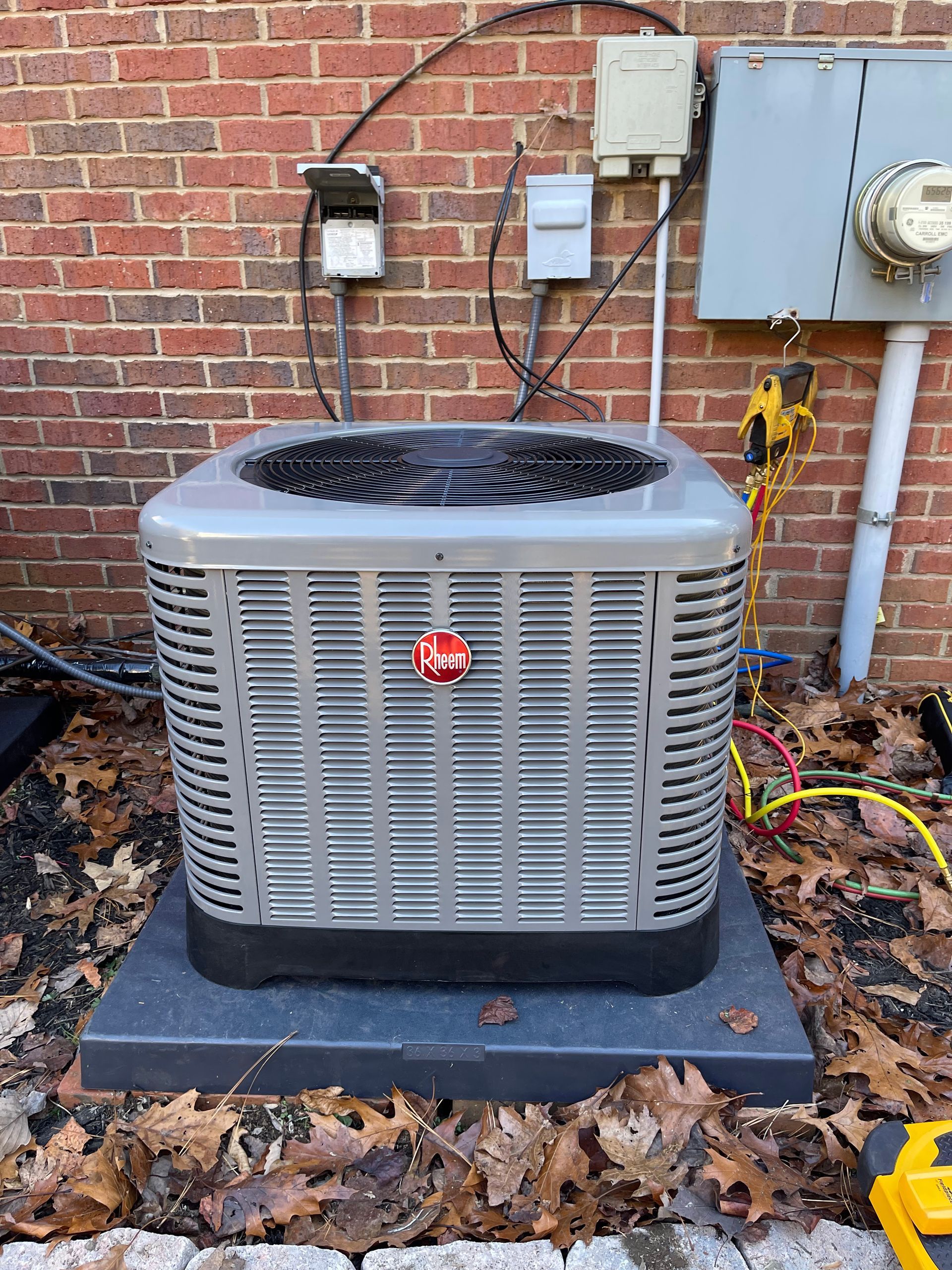 An air conditioner is sitting outside of a brick building.