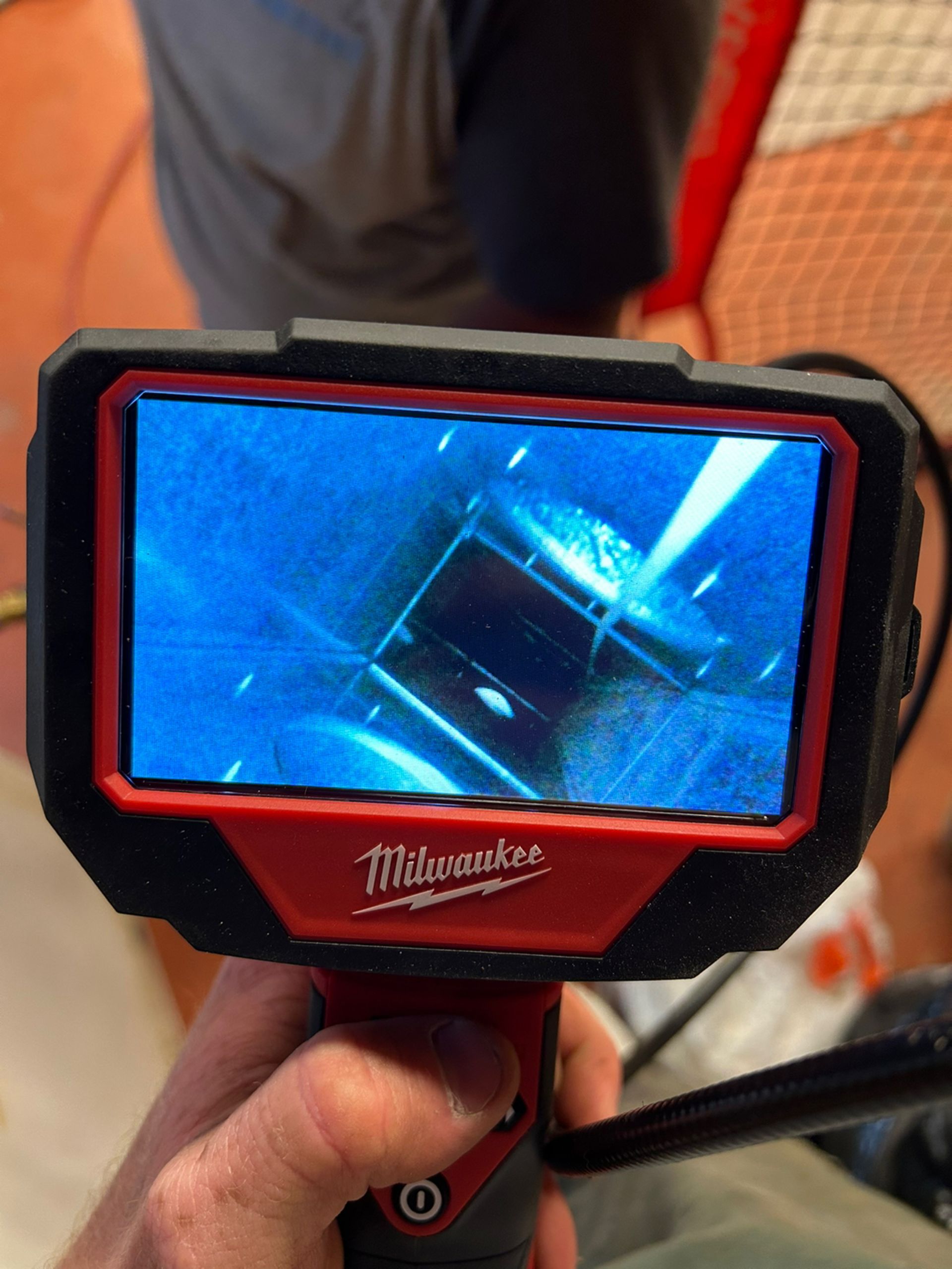 A person is holding a milwaukee camera in their hand