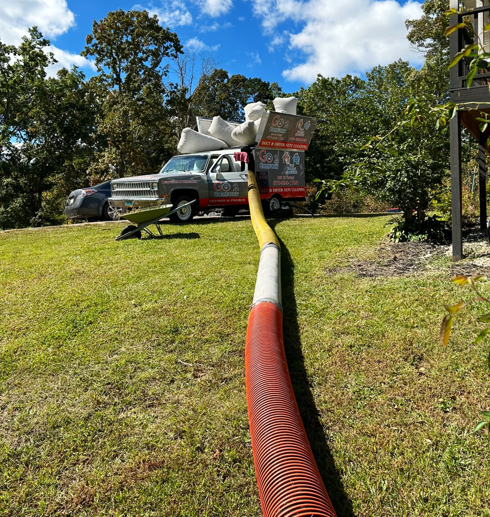 A truck is parked in a grassy field with a hose attached to it.