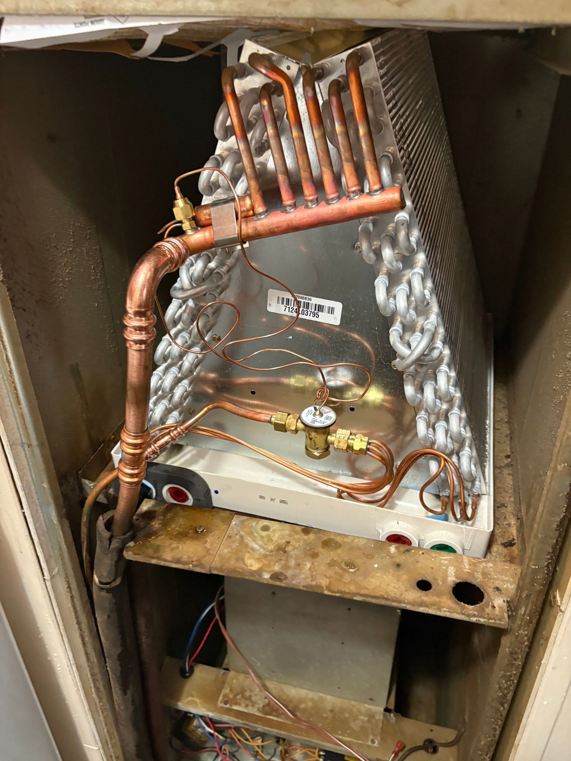 The inside of a refrigerator with copper pipes coming out of it.