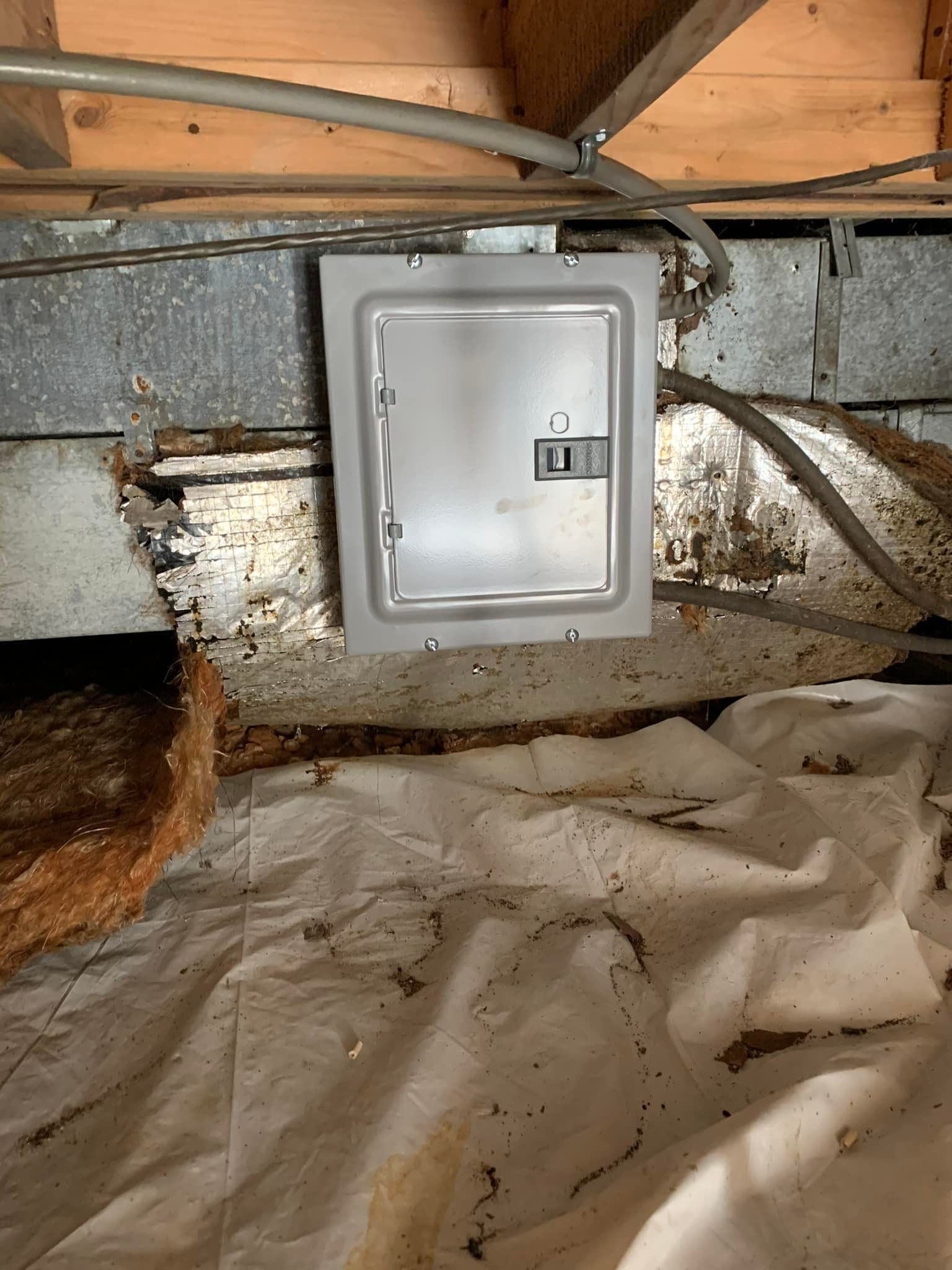 A metal box is hanging from the ceiling of a basement.
