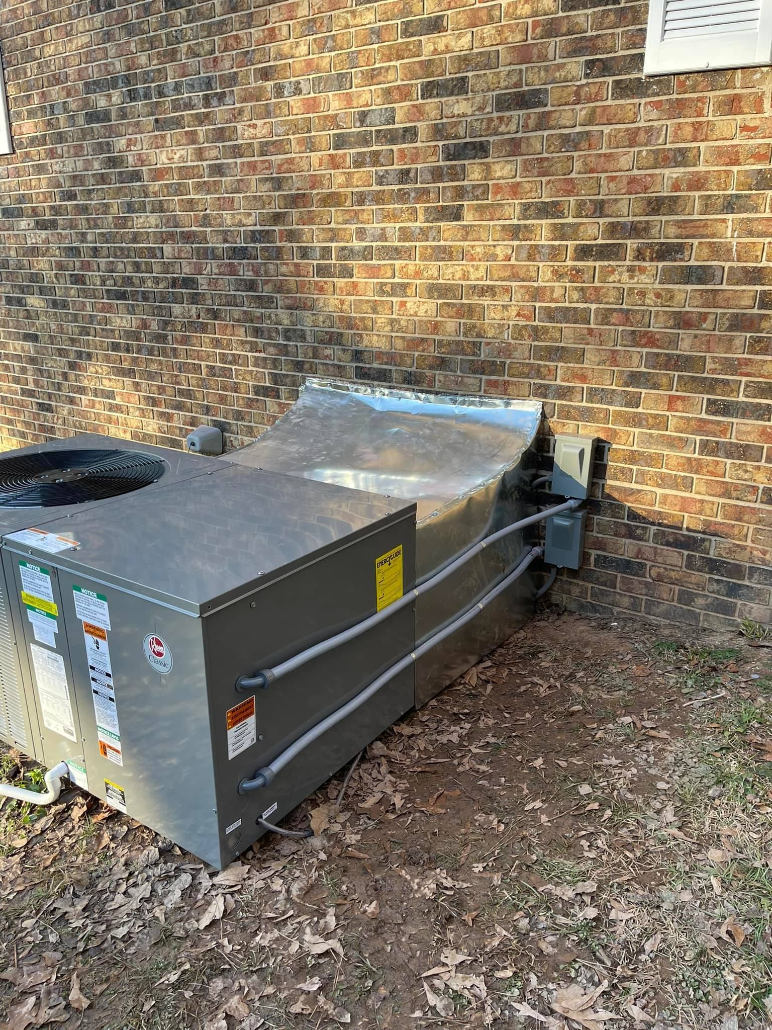 A large metal box is sitting in front of a brick wall.