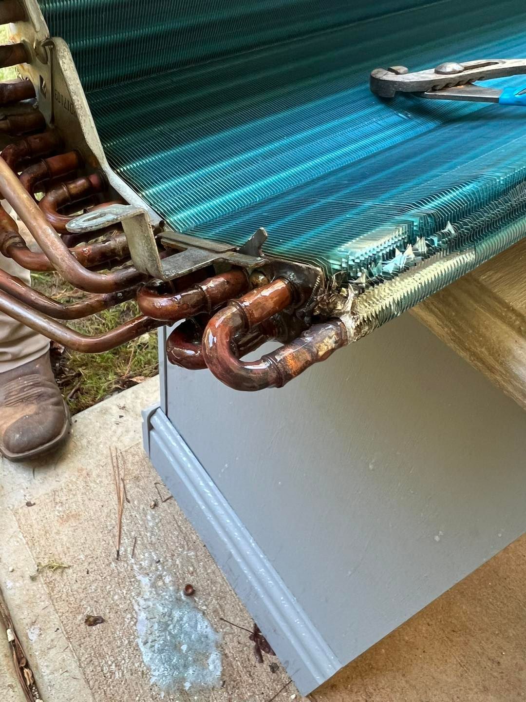 A close up of a refrigerator evaporator with a wrench on it.
