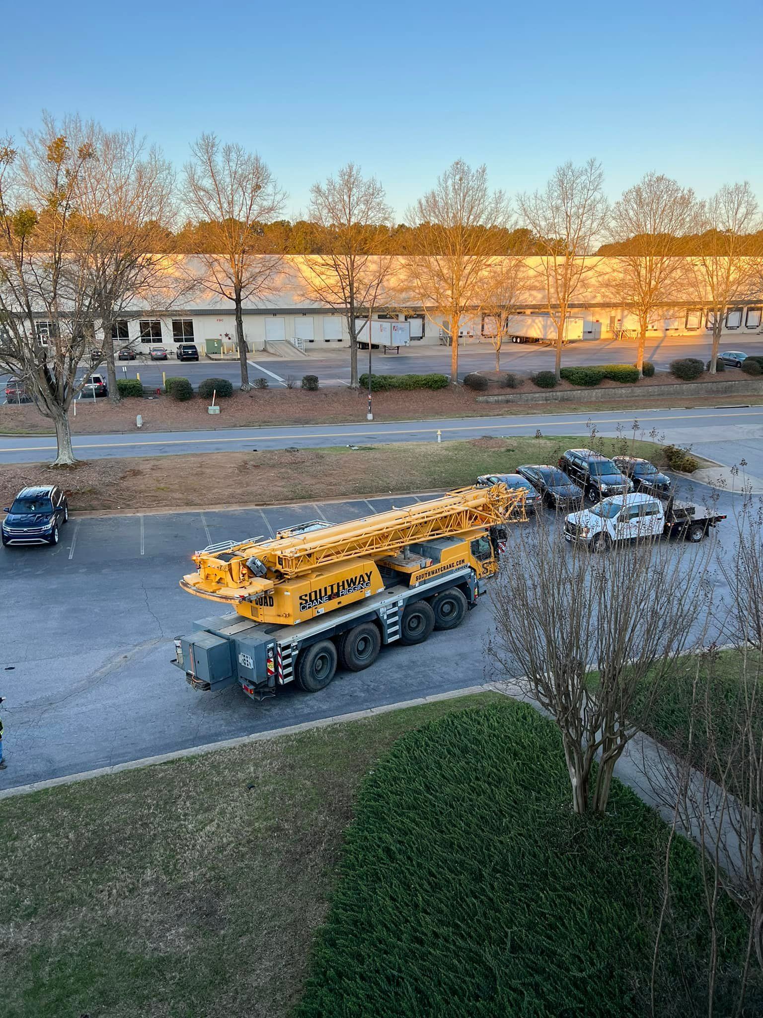 A large yellow crane is driving down a street.