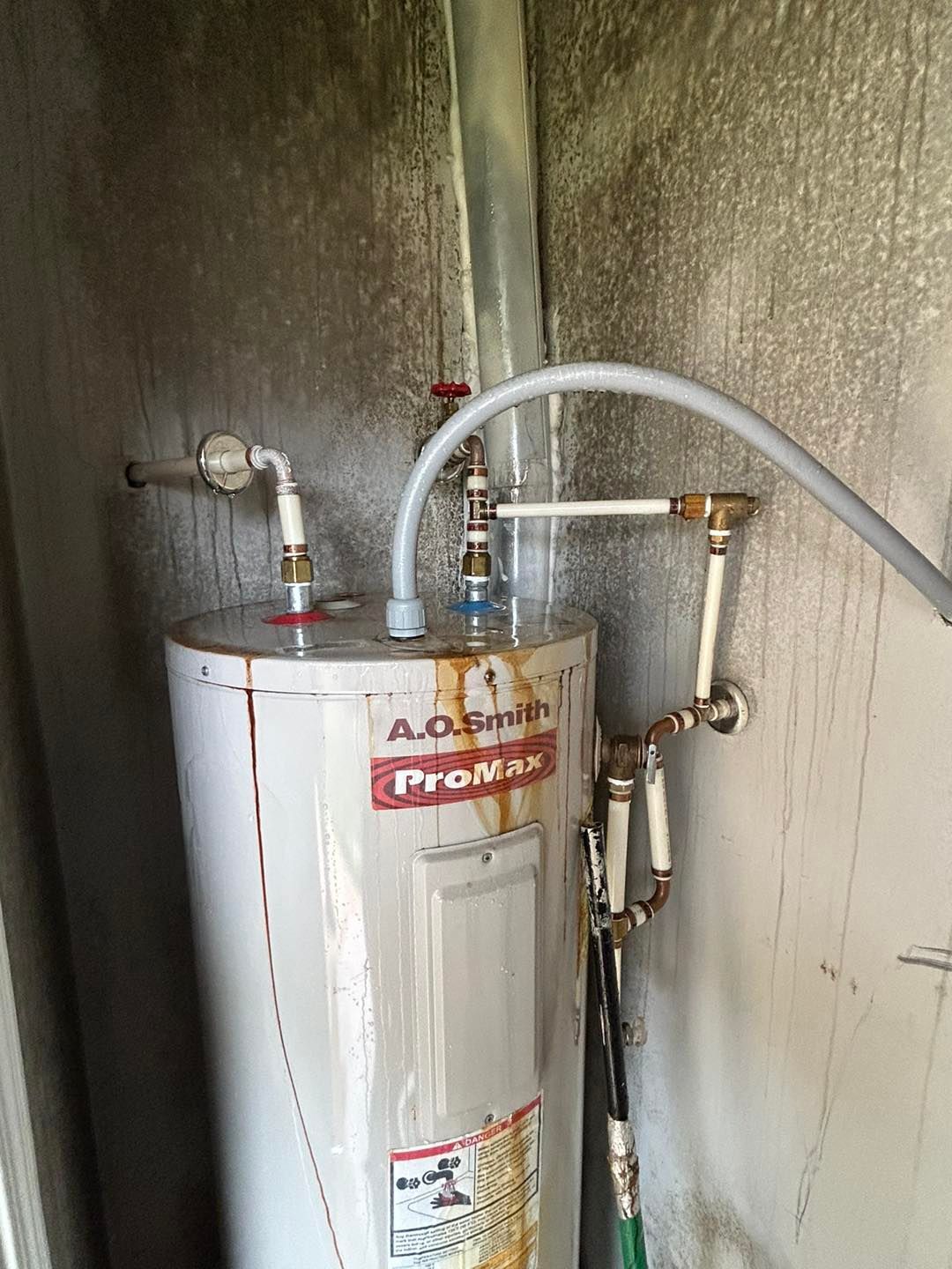 A water heater is sitting in a room next to a wall.