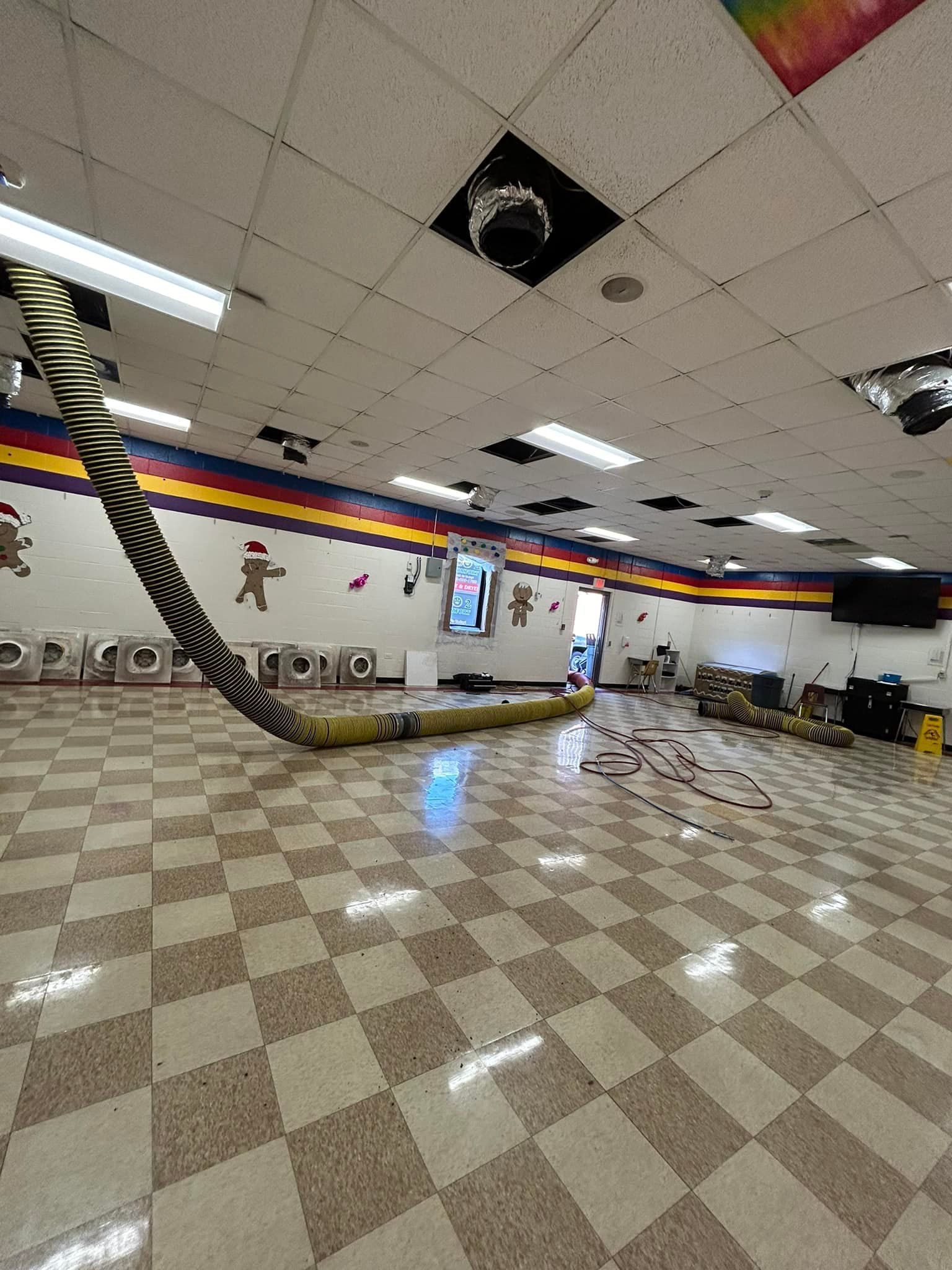 A large room with a checkered floor and a hose hanging from the ceiling.