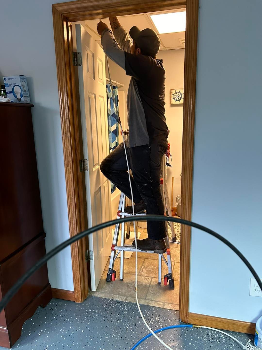 A man is standing on a ladder working on a door.