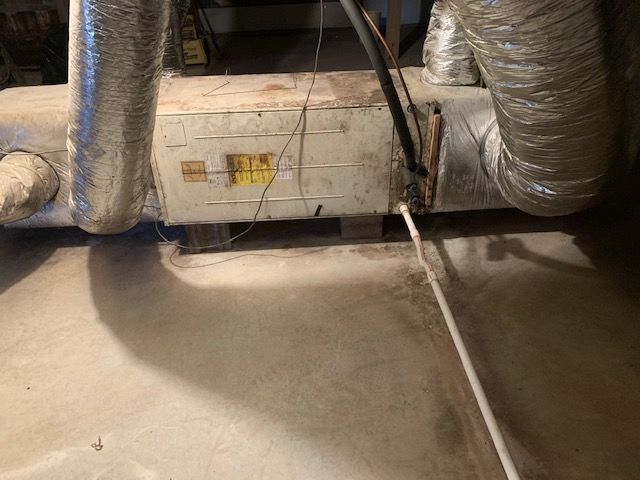 A dirty room with a lot of pipes and wires.