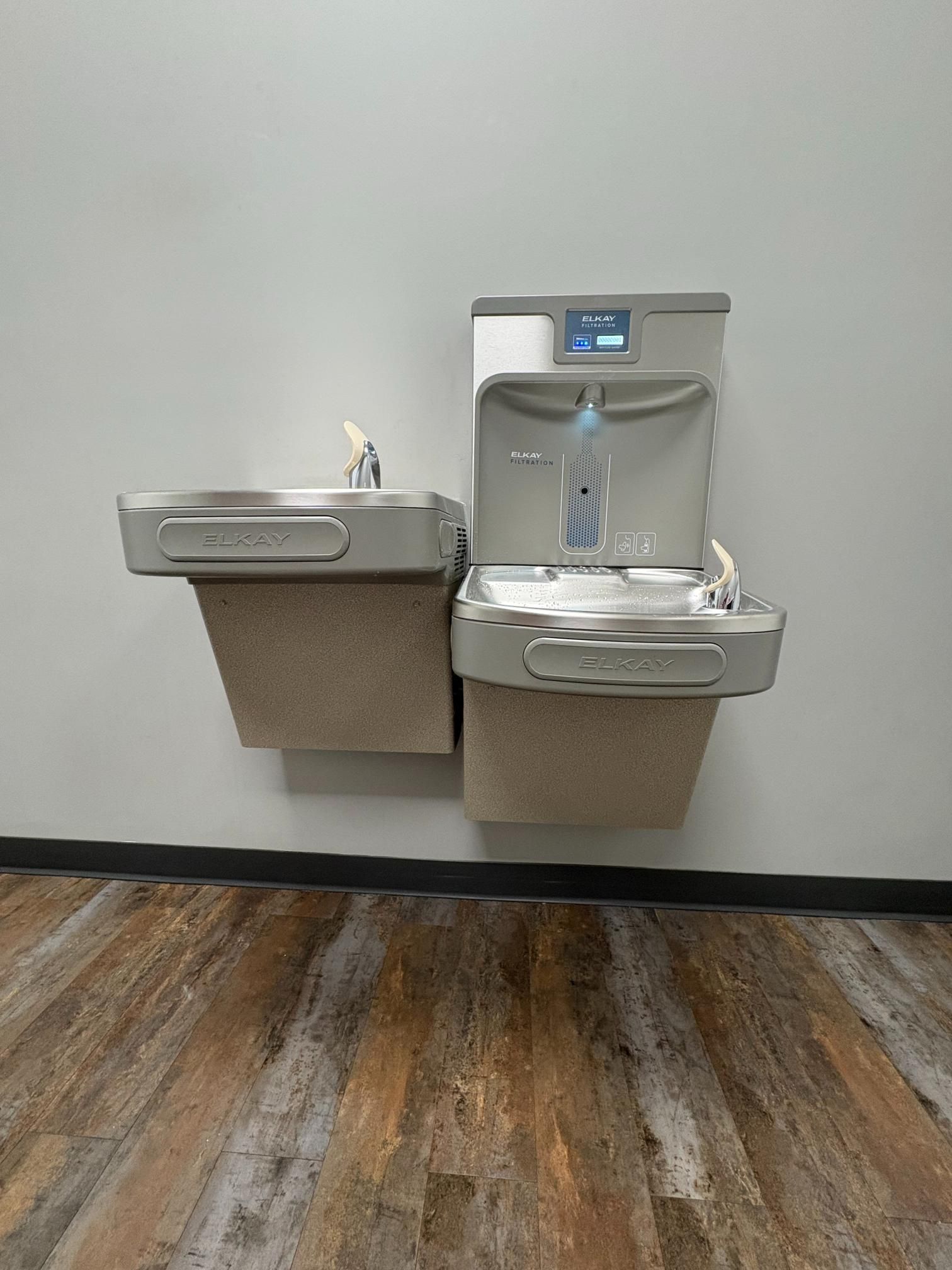 A service truck parked in a grassy yard, with a large, bright orange corrugated hose stretching across the lawn.