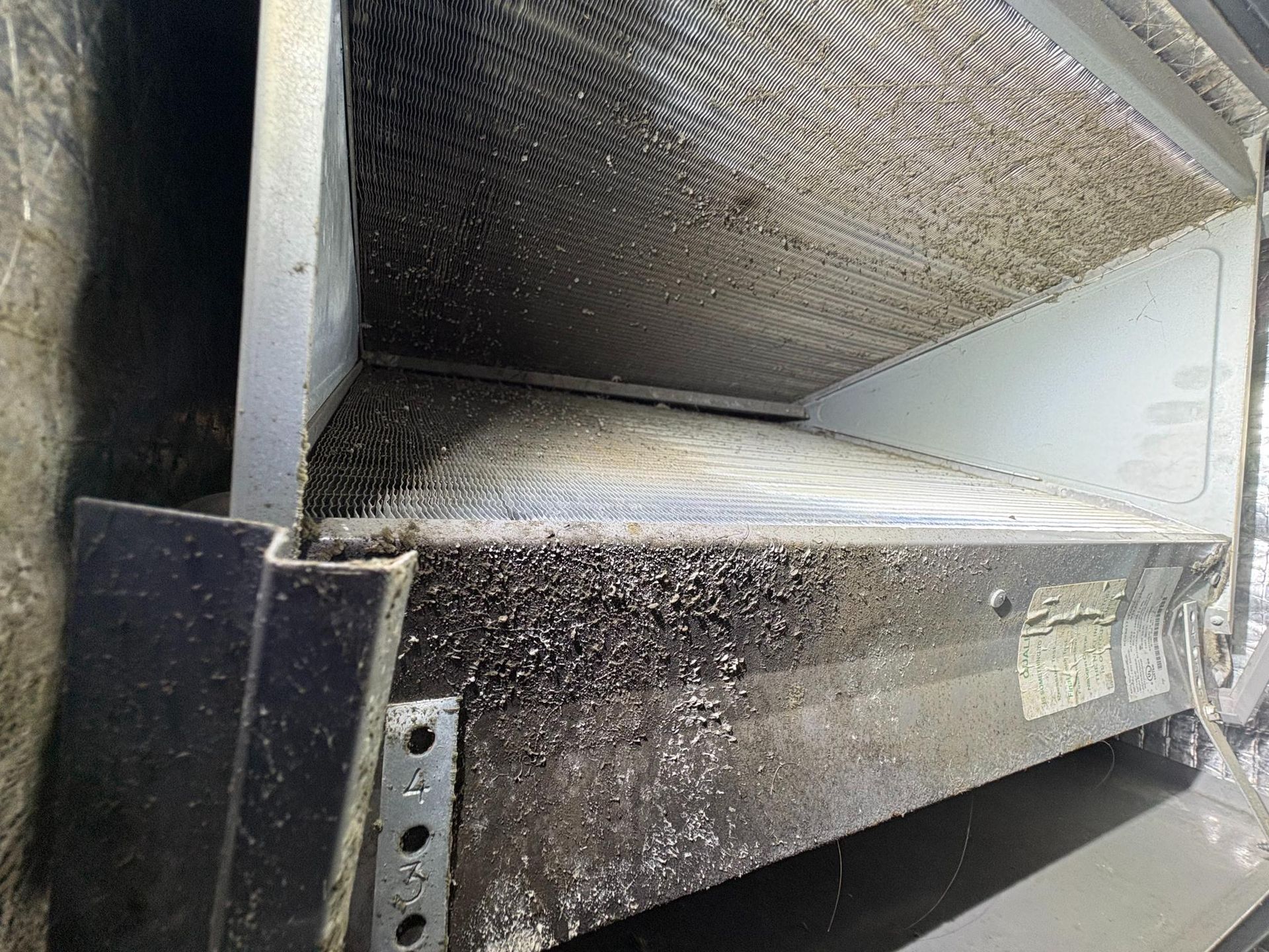 Close-up of a dusty metal conveyor chute with textured surfaces and grease buildup