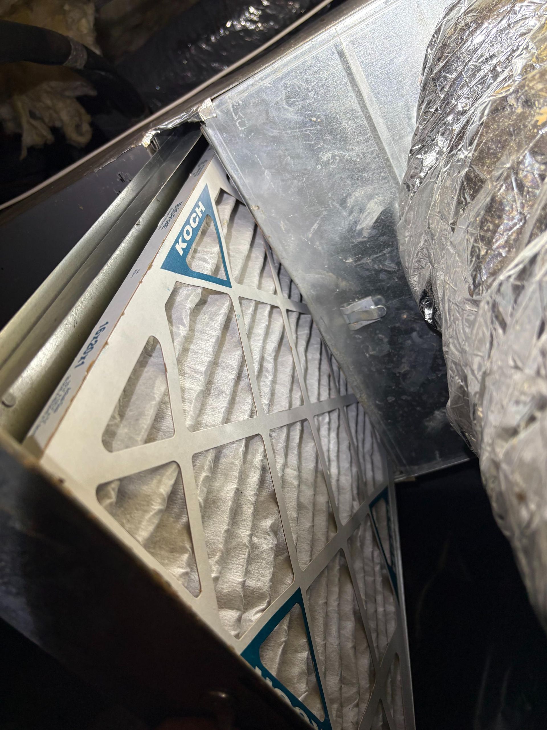 Dusty white metal vent filter inside a dark machine compartment