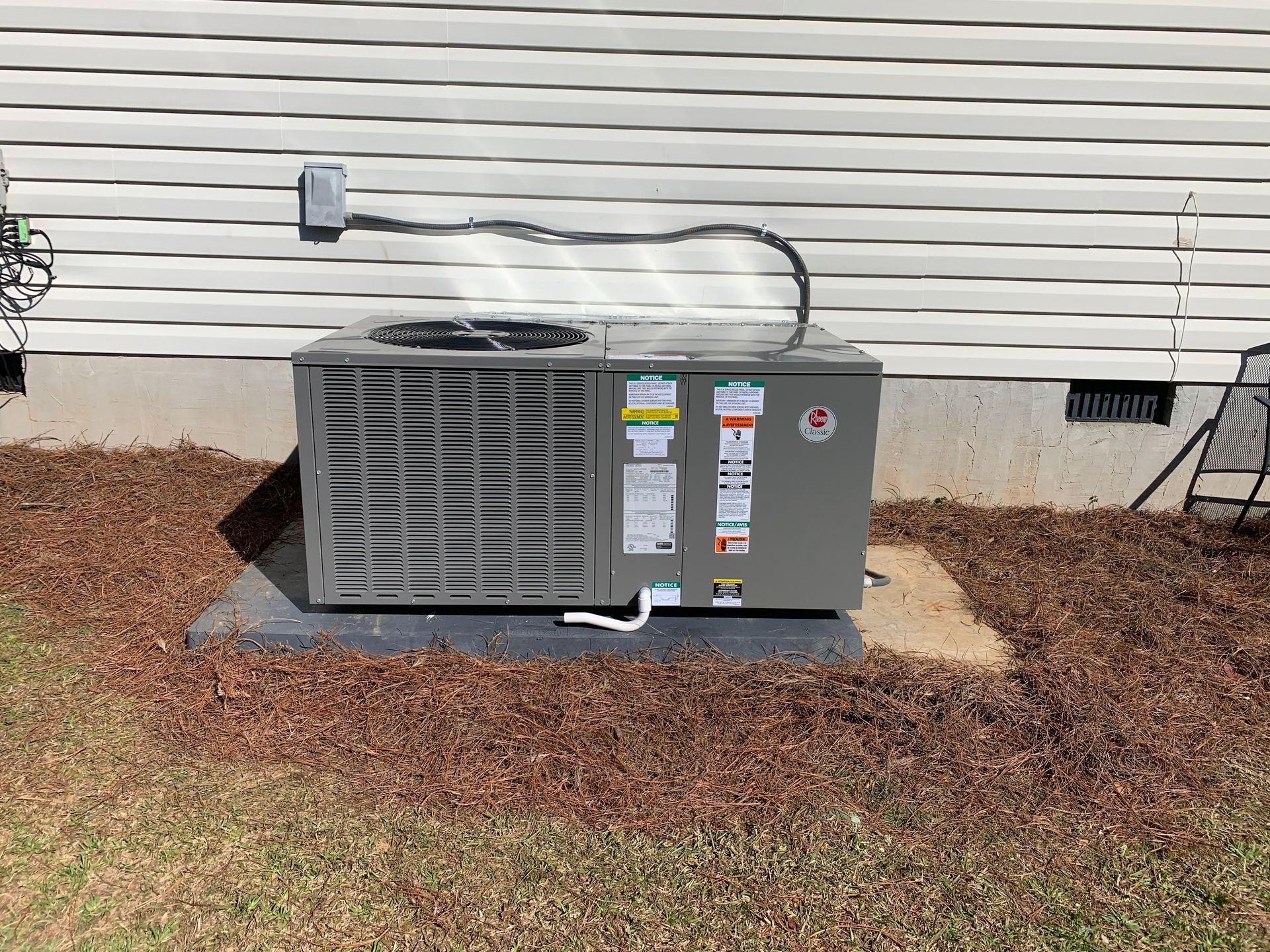 An air conditioner is sitting on the side of a house.
