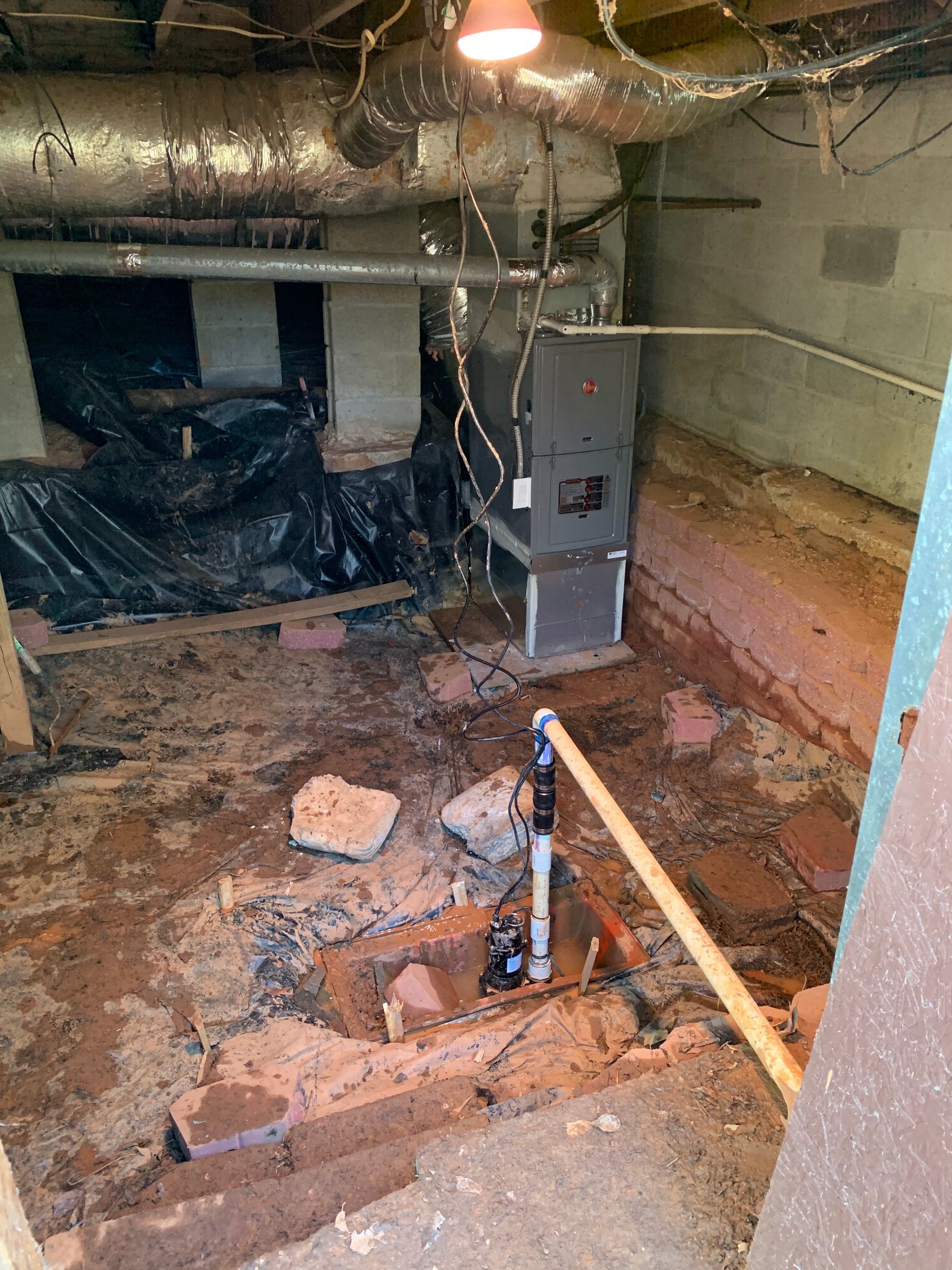 A basement with a furnace and pipes in it.