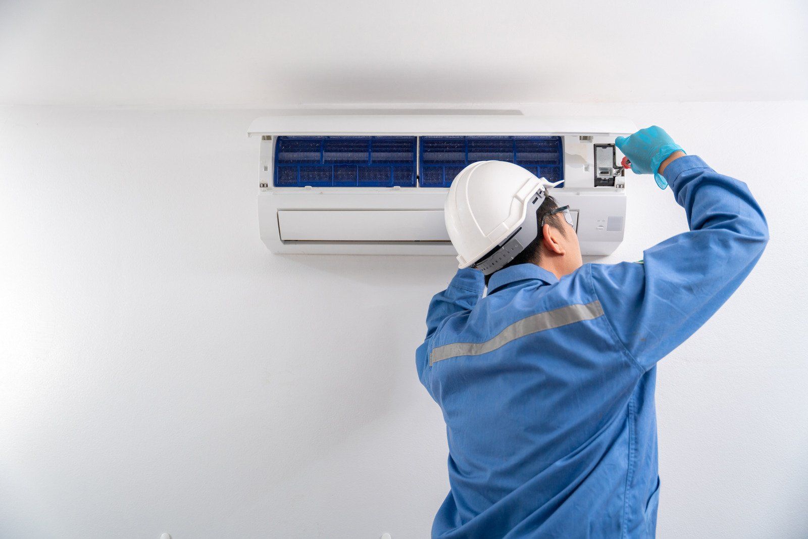 A man is working on an air conditioner in a room.
