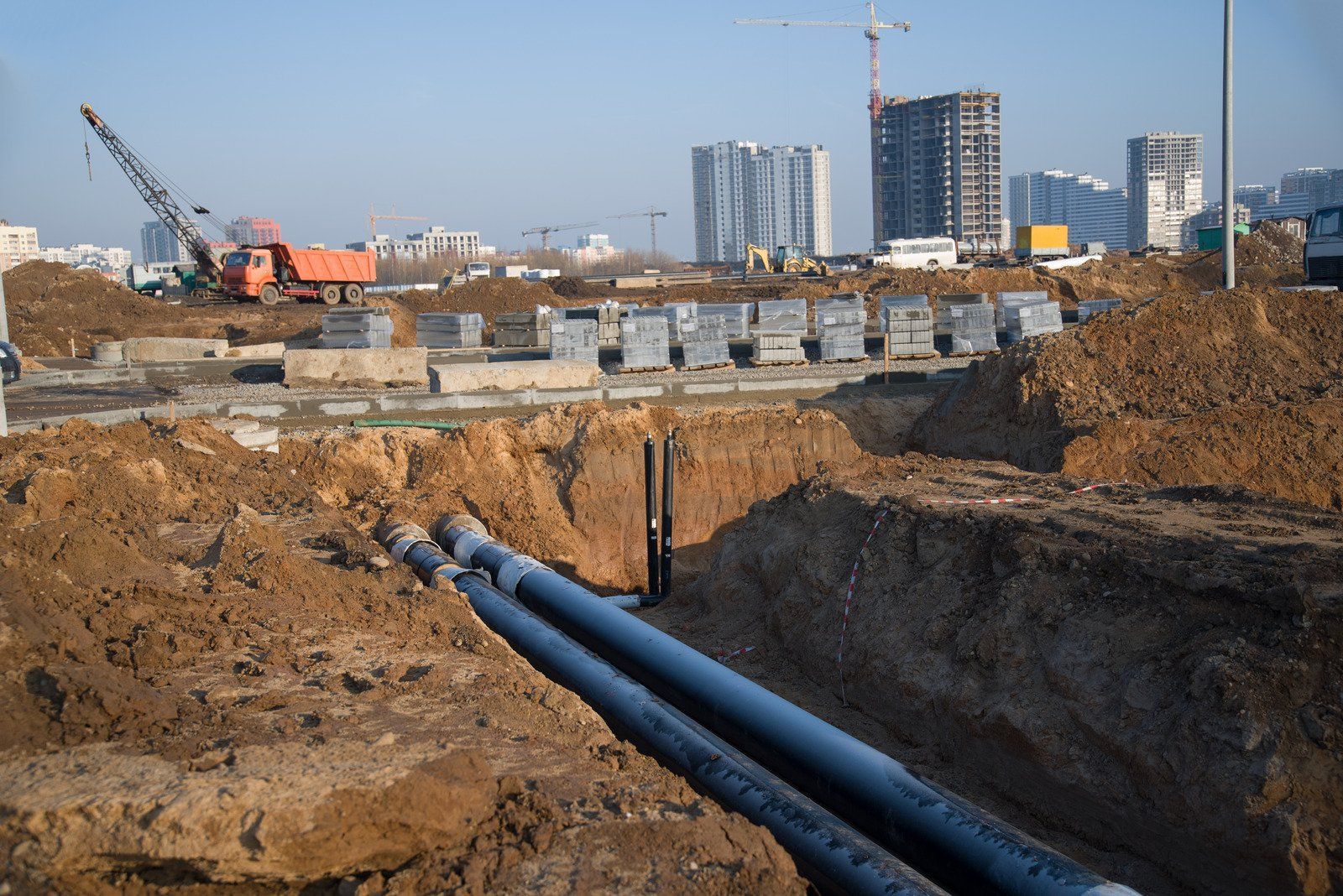 A construction site with a lot of pipes in the dirt.