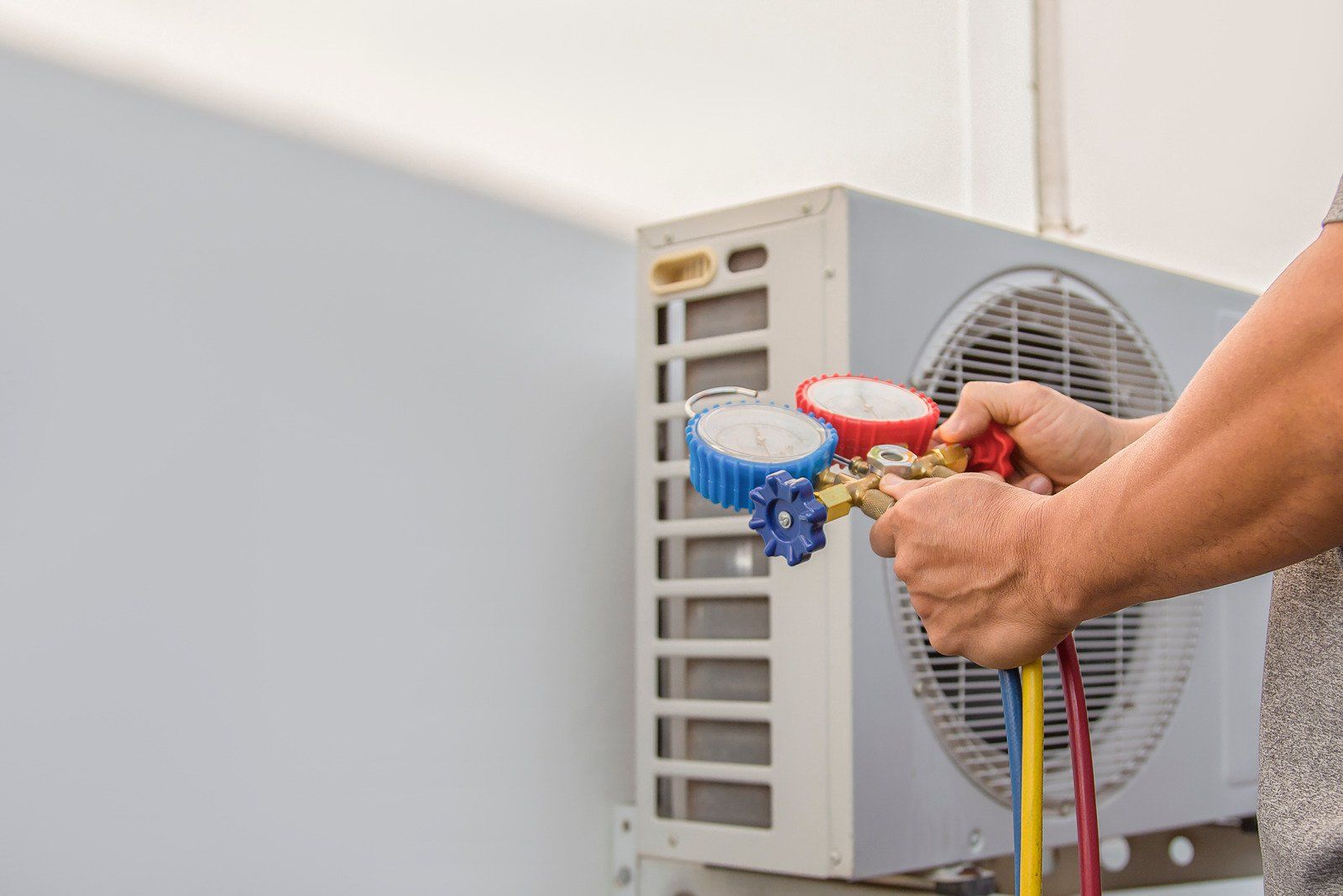 A man is working on an air conditioner outside of a building.