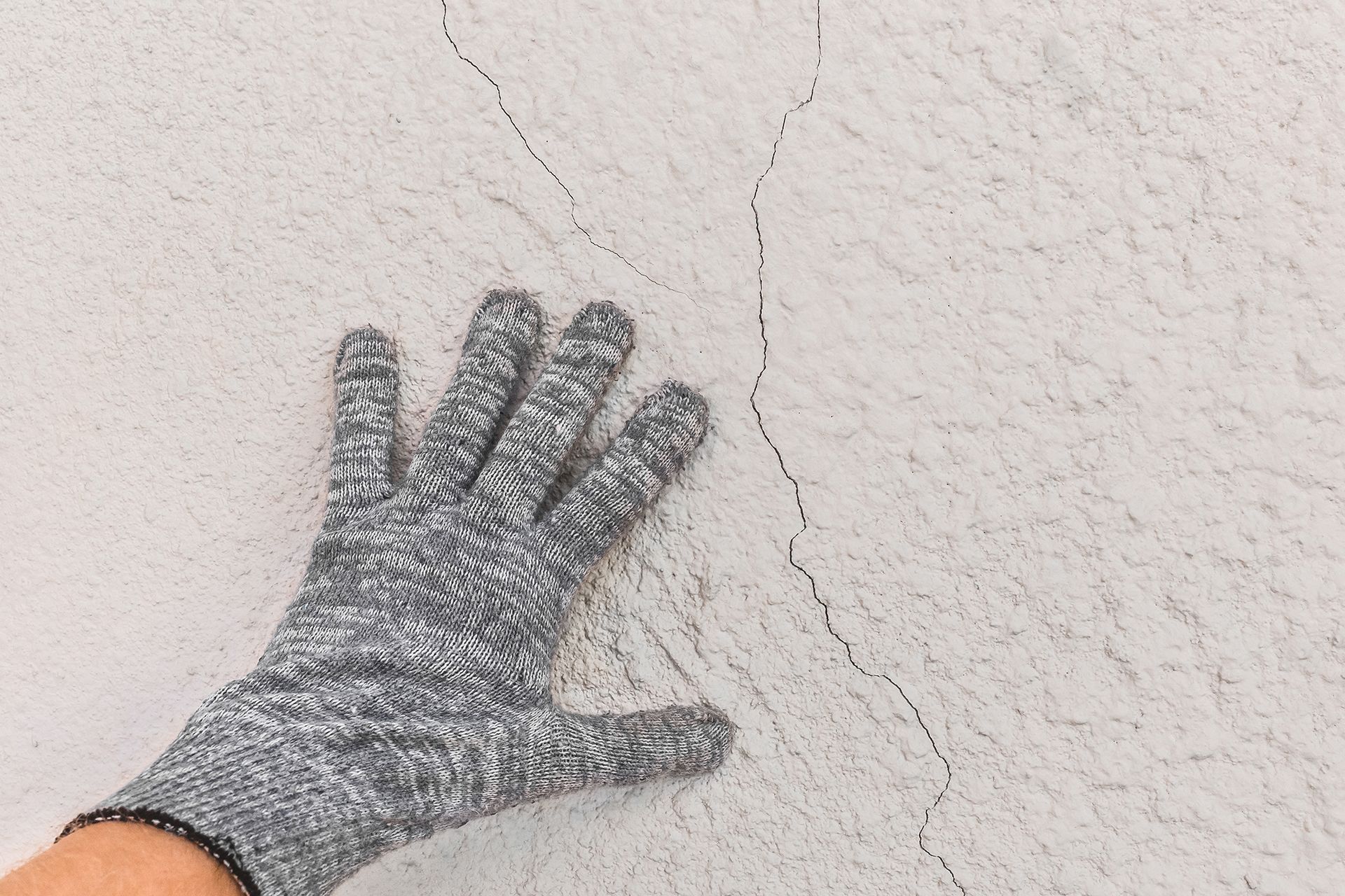 a person wearing a glove is touching a white wall