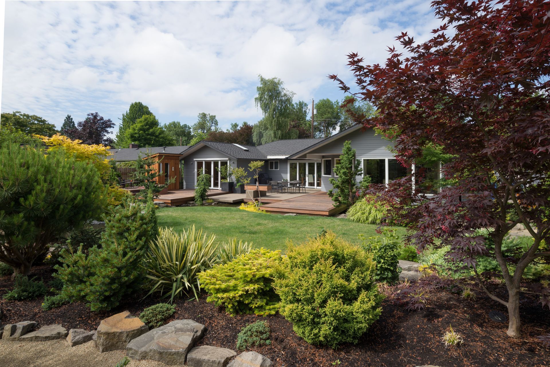 A house is surrounded by a lush green lawn and trees