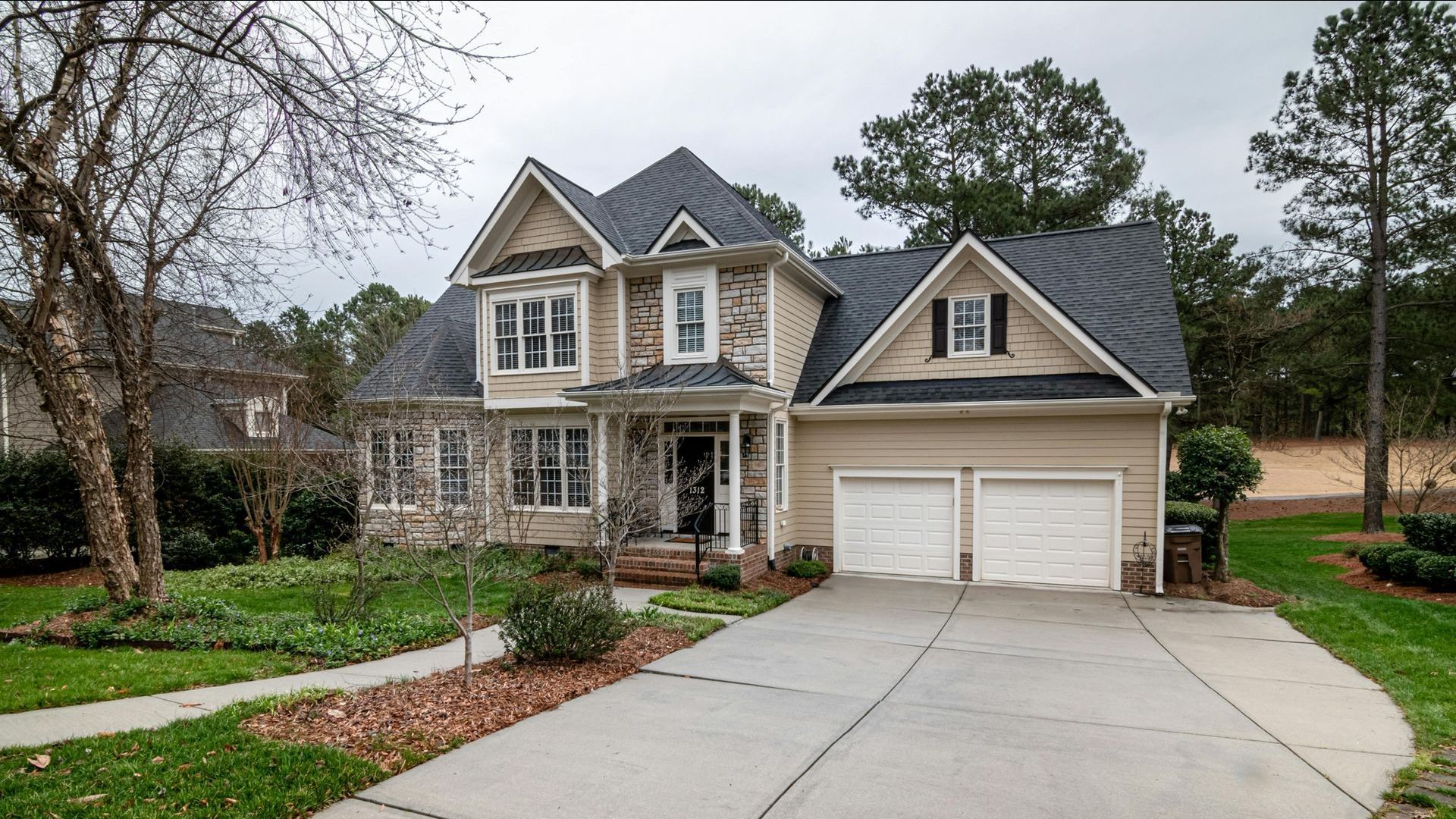 A brick house with a circular garden in front of it.