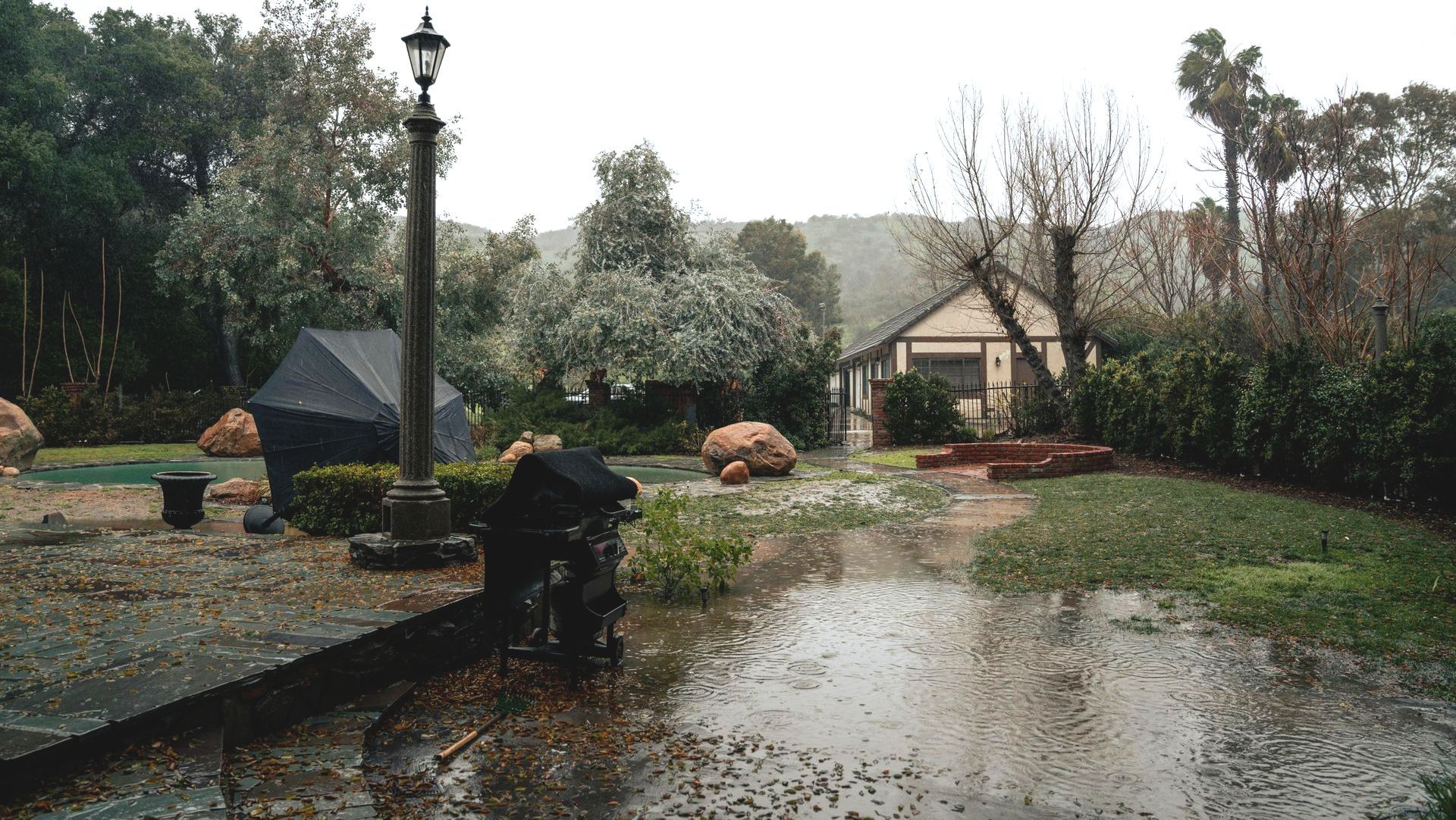 A backyard with a lot of rocks and a puddle of water.