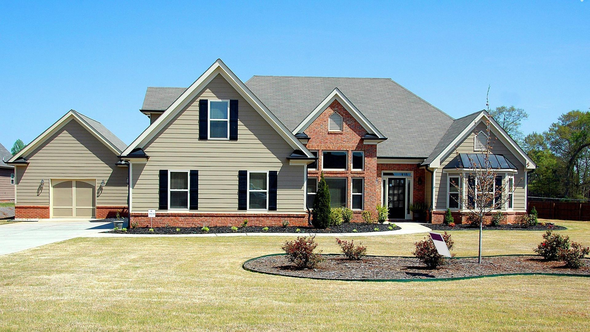 A house with a large lawn and trees in front of it.