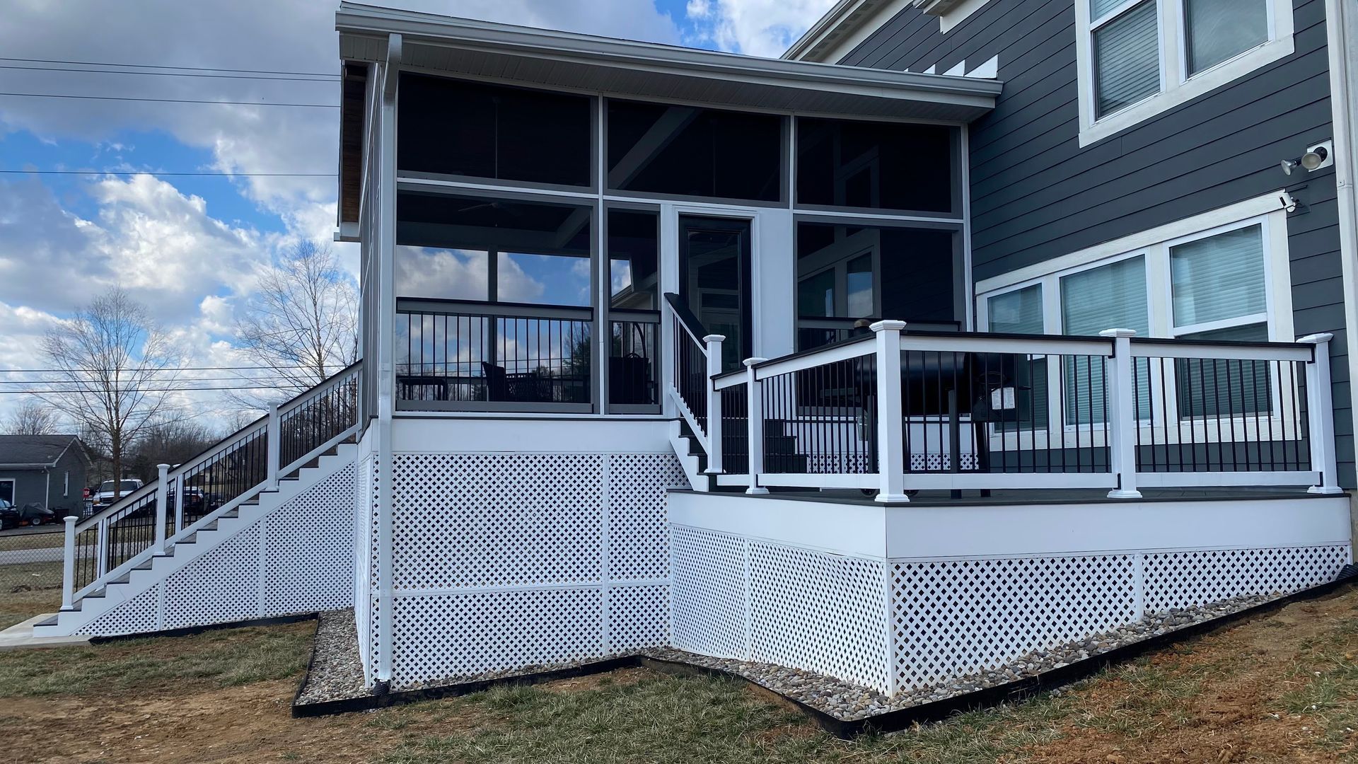 Play set with slide and climbing wall in a yard with wood chips, next to a white shed.