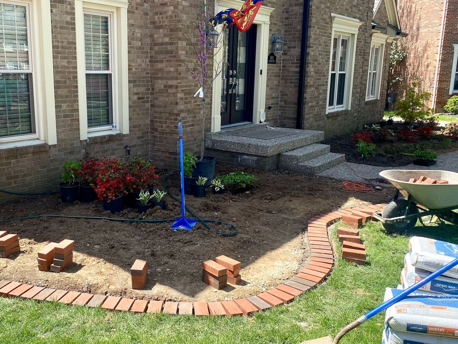 Red brick home with a stamped concrete walkway, garden, and black mulch.