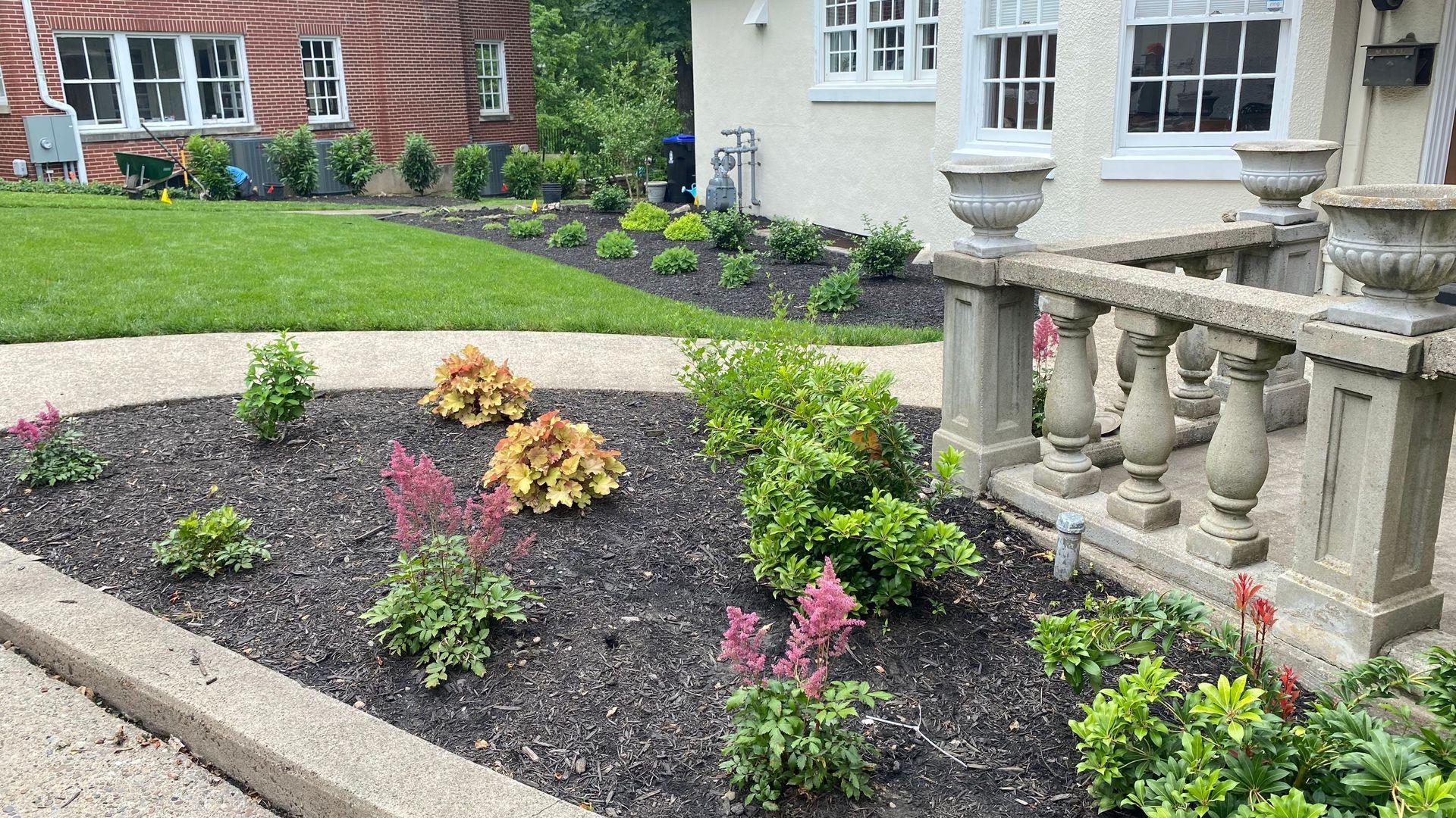 Landscaped front yard with mulch beds, flowers, and a stone porch.