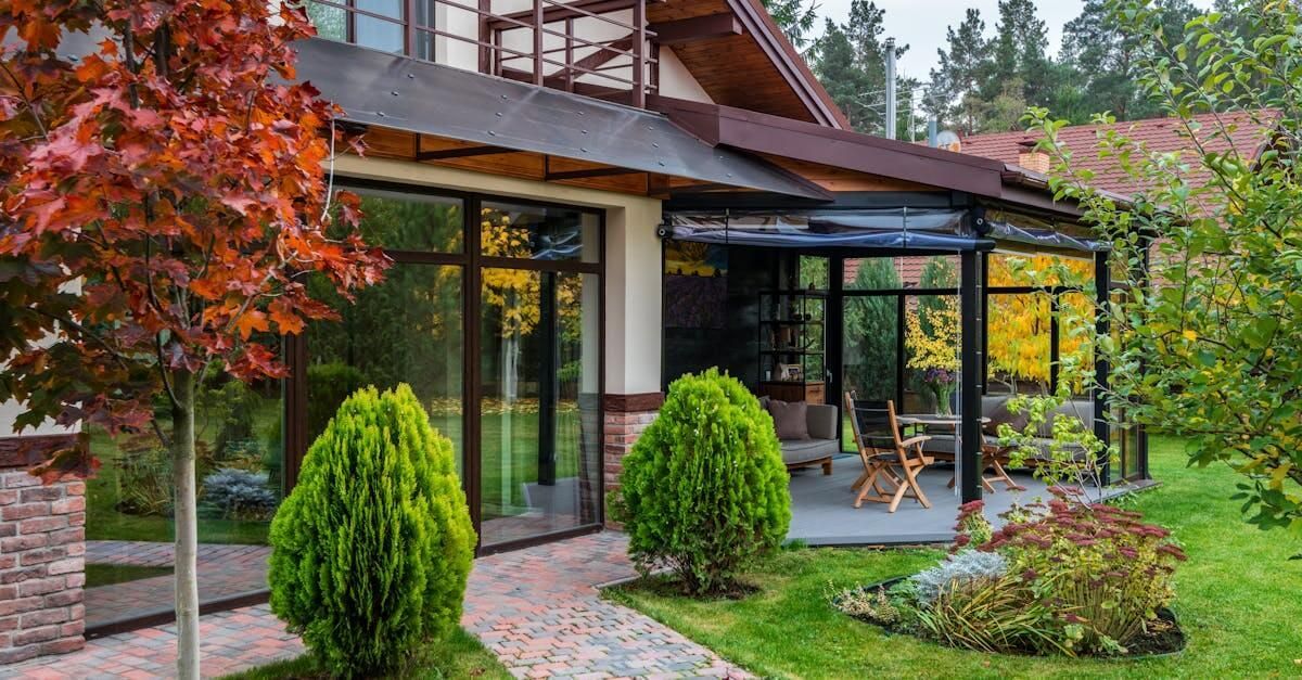 A large house with a large patio in front of it surrounded by trees and bushes.