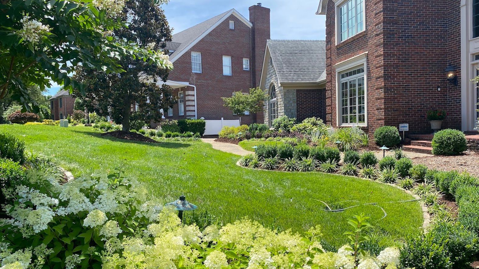 A large brick house with a lush green lawn in front of it.