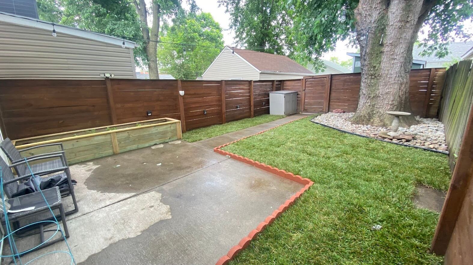 A backyard with a wooden fence and a lush green lawn.