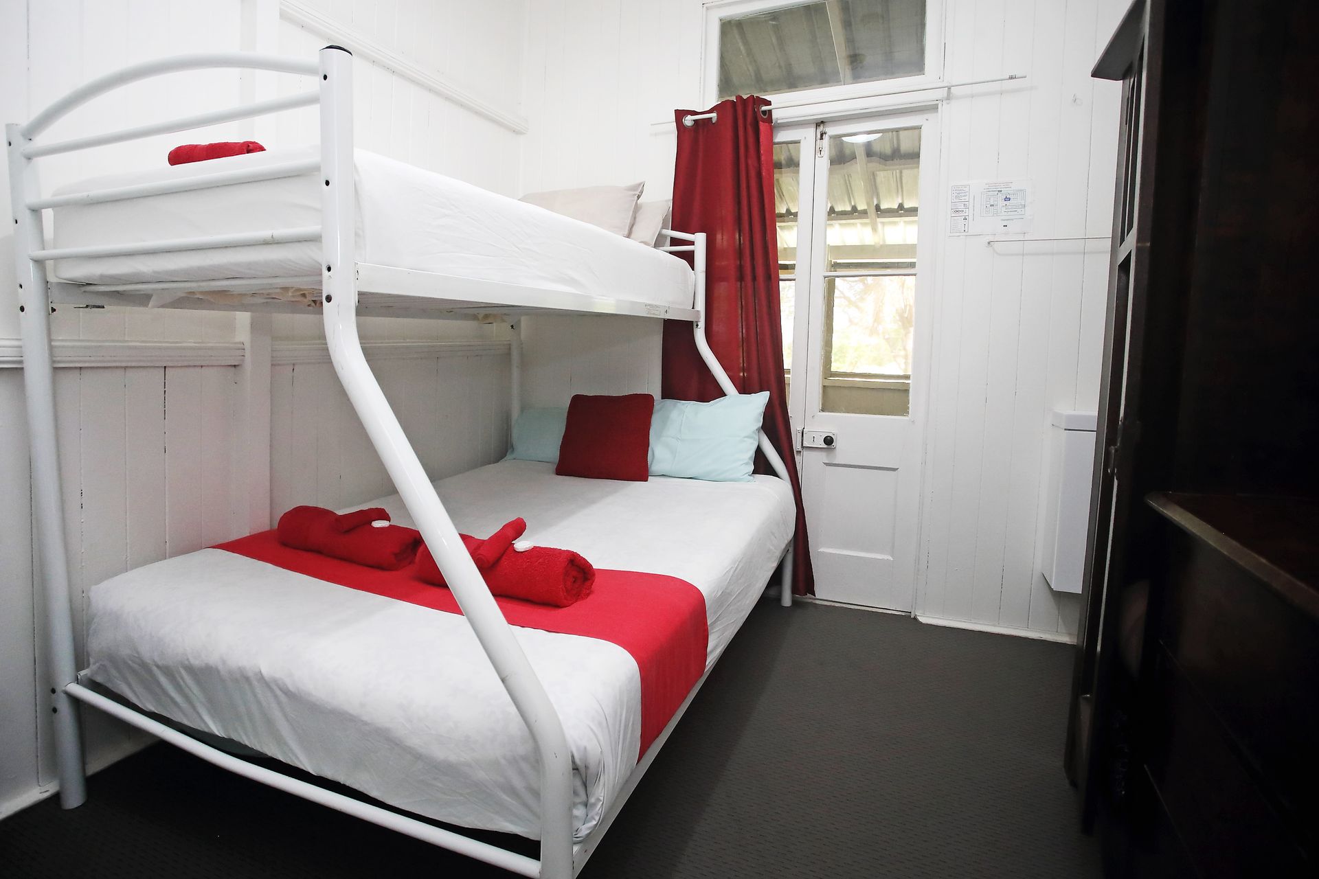 Bunk bed in a white-walled room with red and blue accents. A door is to the right.