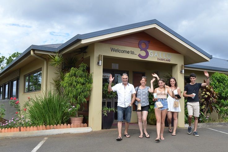 Group of people waving in front of a building with a sign that says “Satori Gardens”.