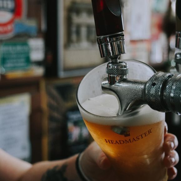Beer being poured from a tap into a glass, with a foamy head.