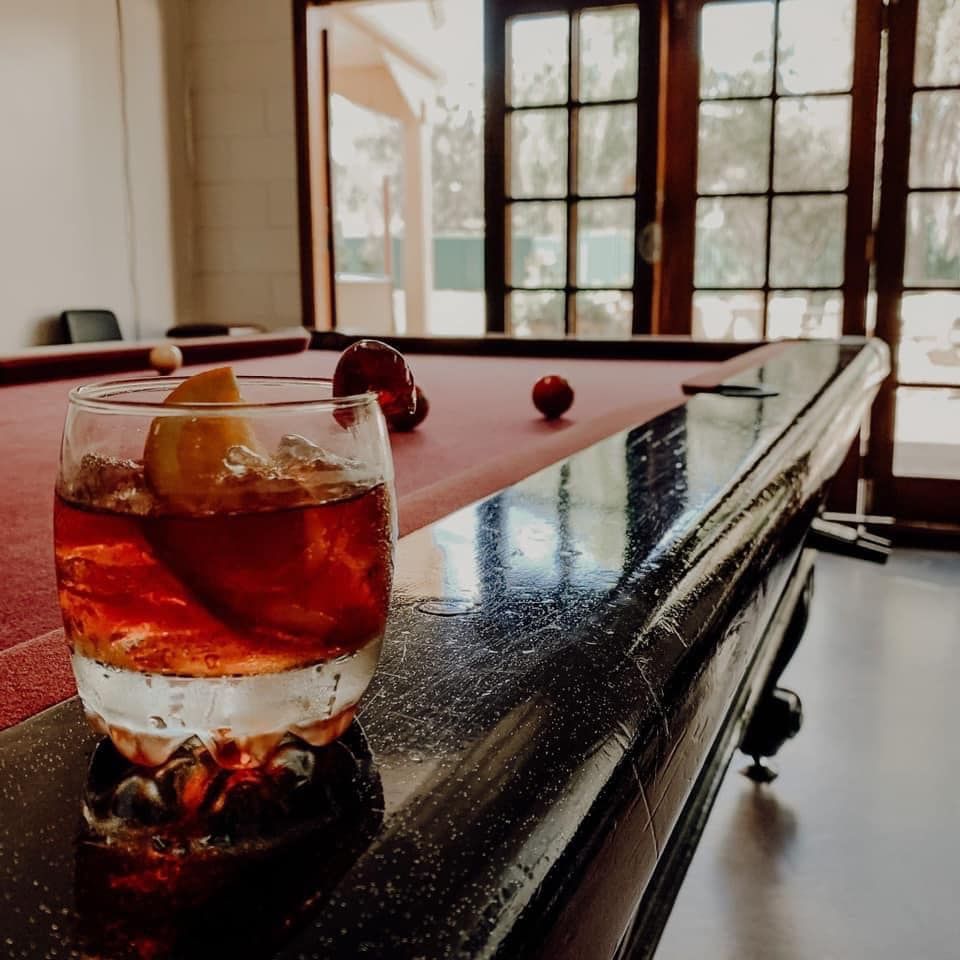 Cocktail on the edge of a pool table with a window in the background.