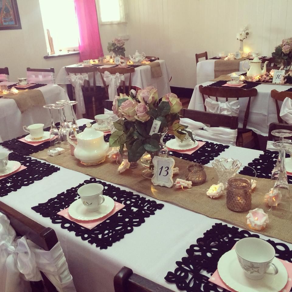 Tables set for an event, floral centerpieces, teacups, pink and black accents.