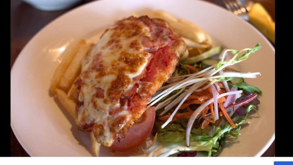 Chicken parmigiana with fries and salad on a white plate.