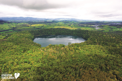 Overhead view of a crater lake surrounded by lush green forest in Atherton Tablelands, Queensland, Australia.