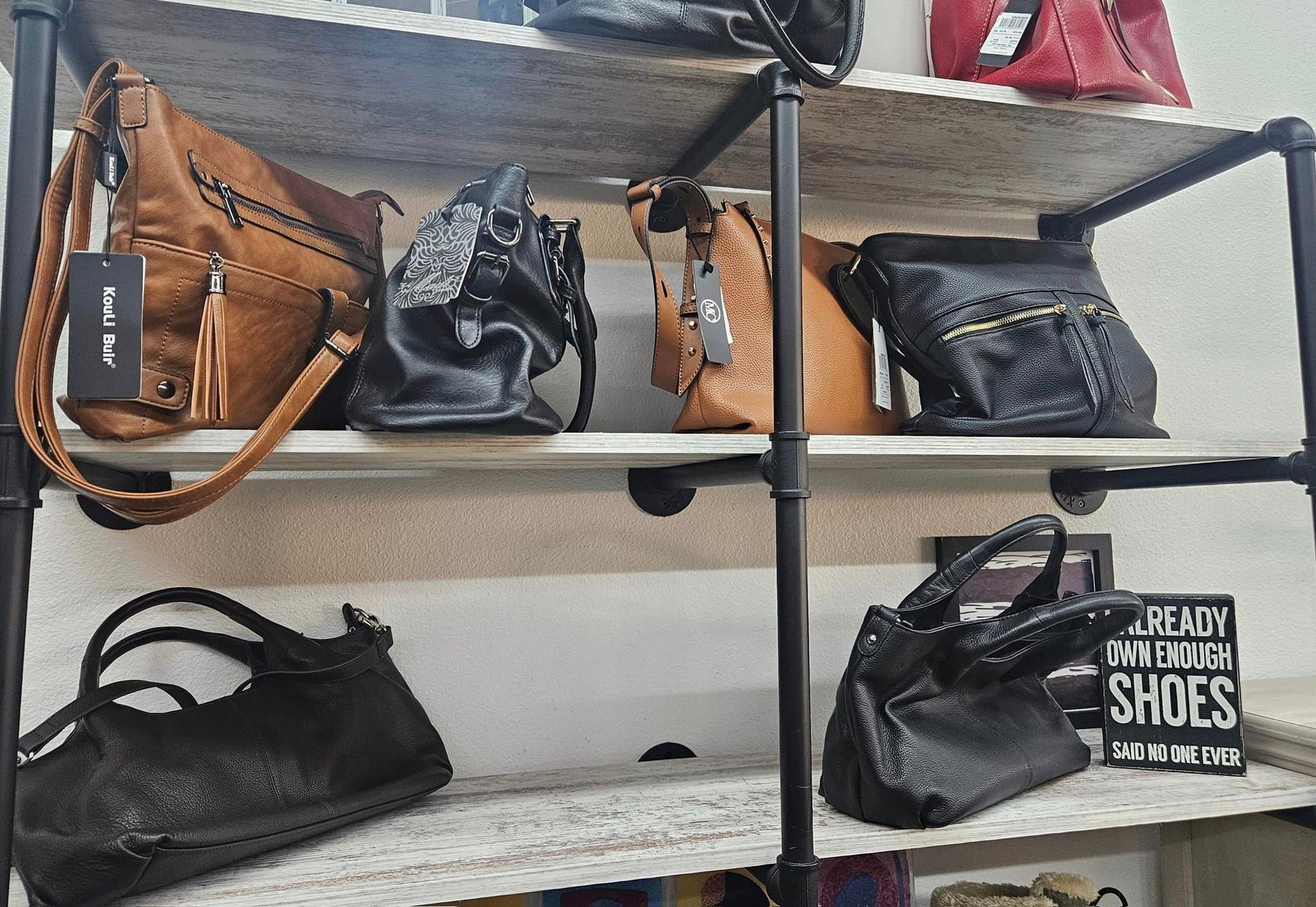 A shelf filled with handbags and a sign that says shoes