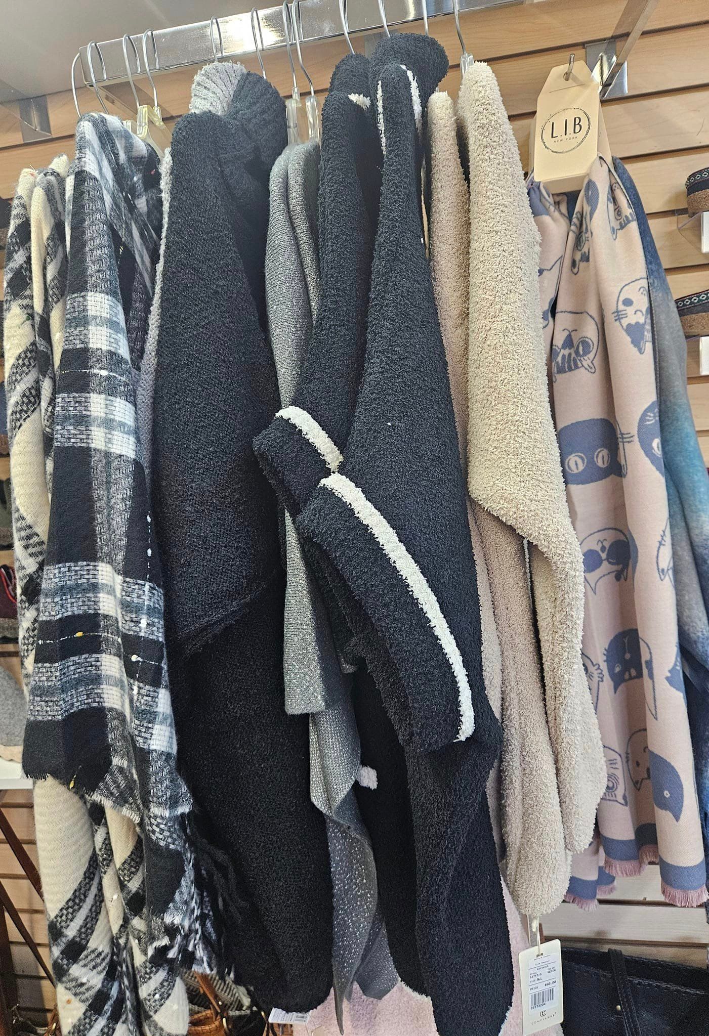 A bunch of scarves are hanging on a rack in a store.