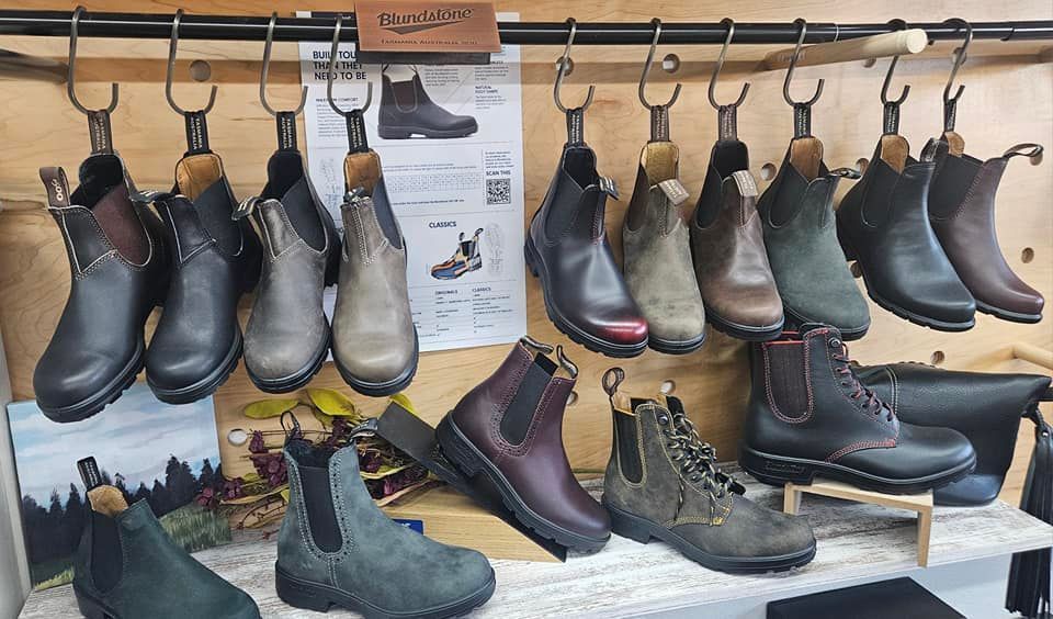 A variety of boots are hanging on a rack in a store.