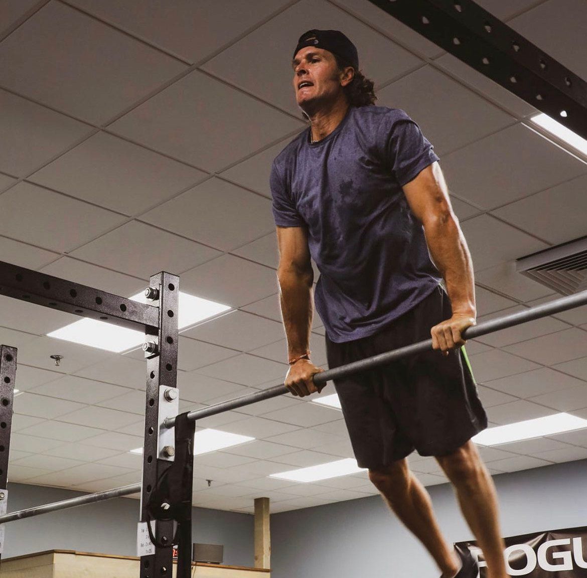 A man is doing a pull up on a bar in a gym