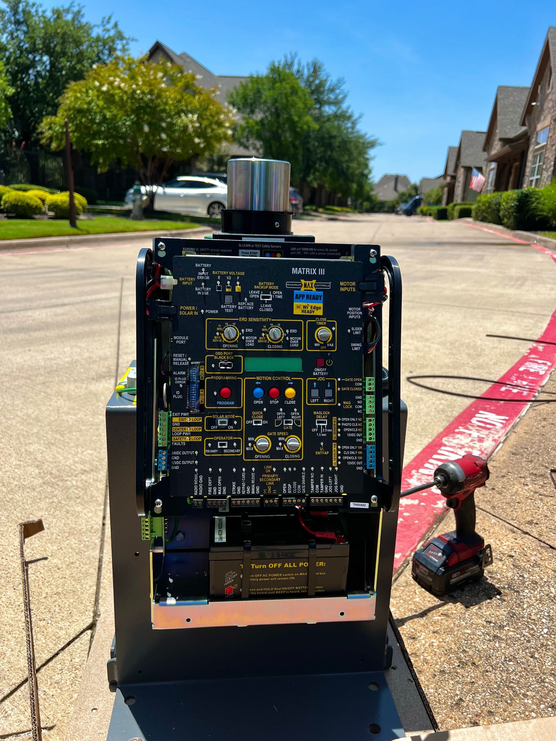 Black control panel on cart outside with a cordless drill and battery.